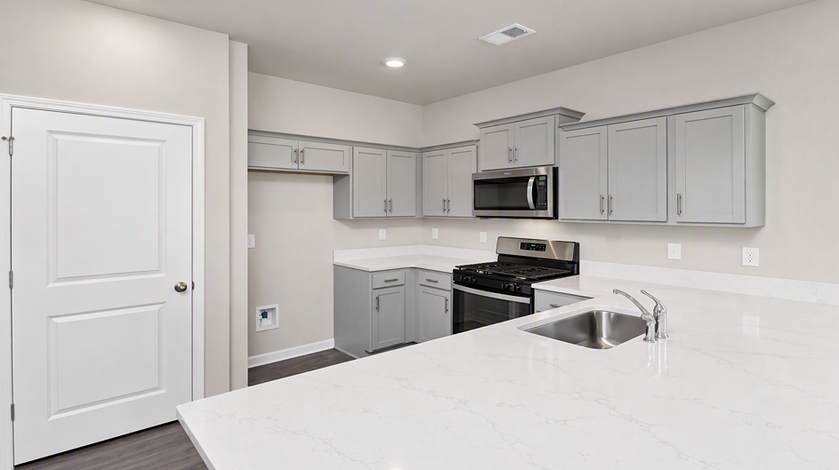 White quartz countertops and gray cabinets in the kitchen space of new home for sale in Ferry Grove
