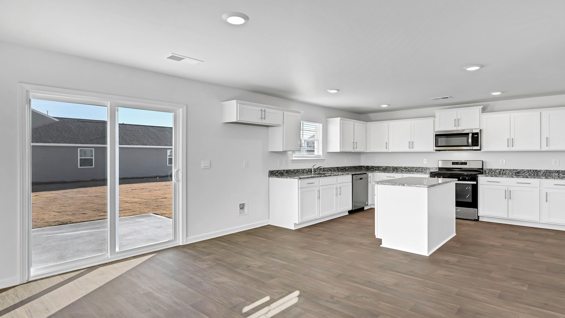 Open concept dining and kitchen spaces with natural light from the glass back doors