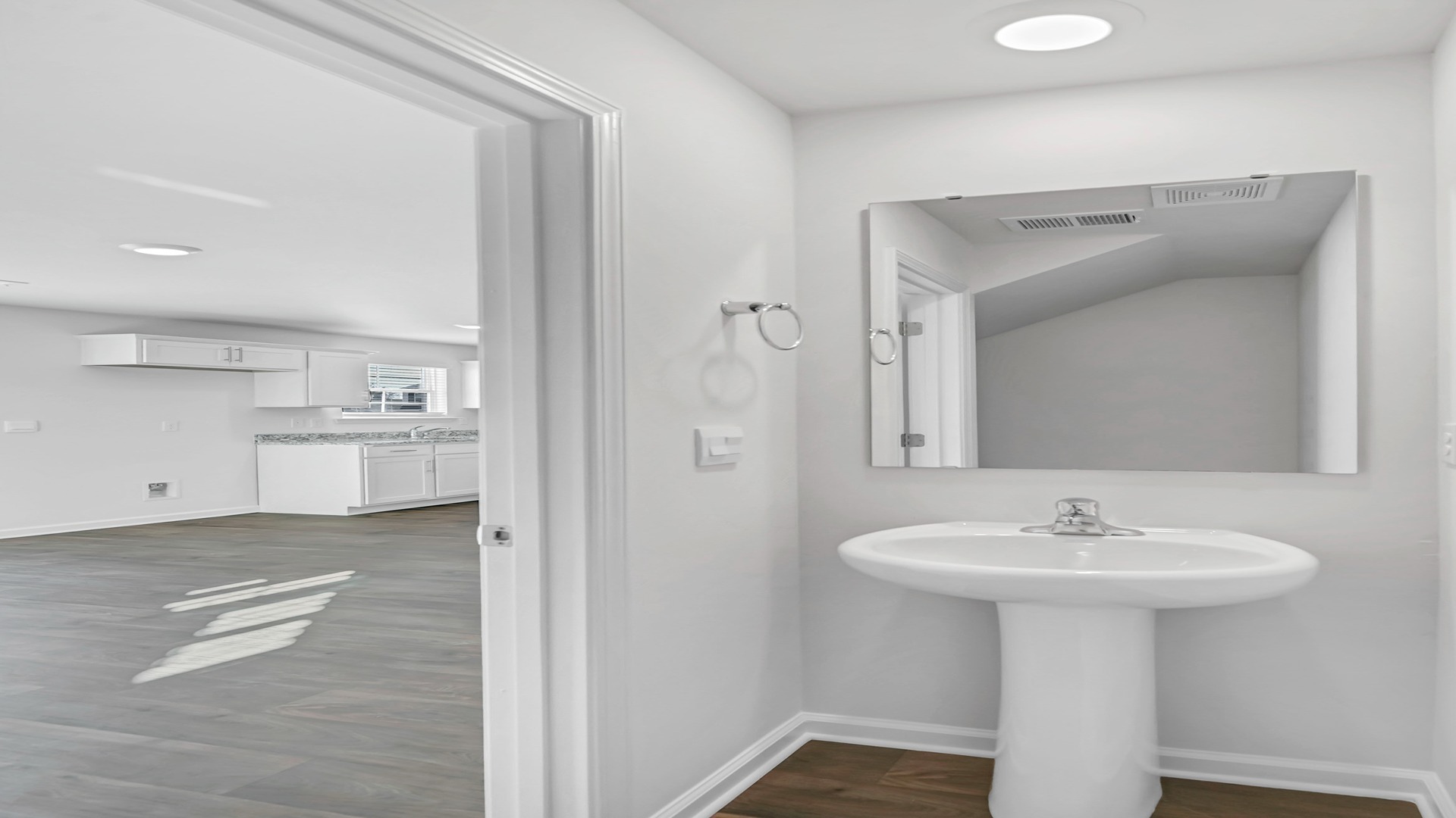 First-floor powder room with pedestal sink and a mirror