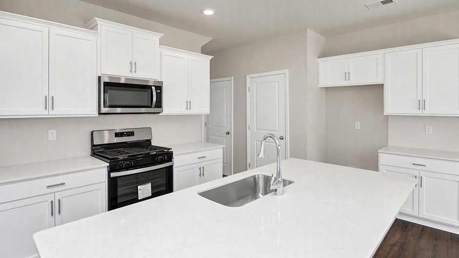 White quartz countertops and white cabinets finish the kitchen area of the new home for sale