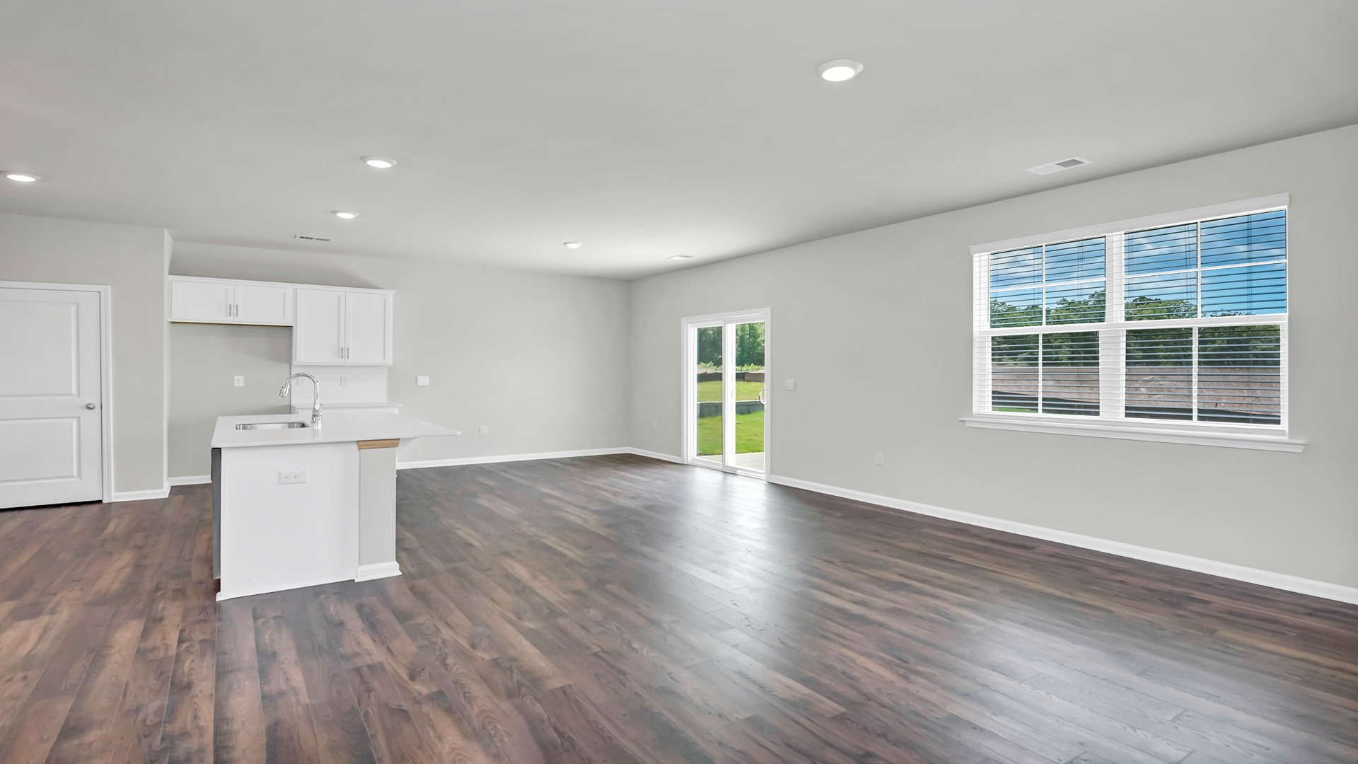 Open first floor of the Aisle floorplan with matching vinyl floors and windows for natural light