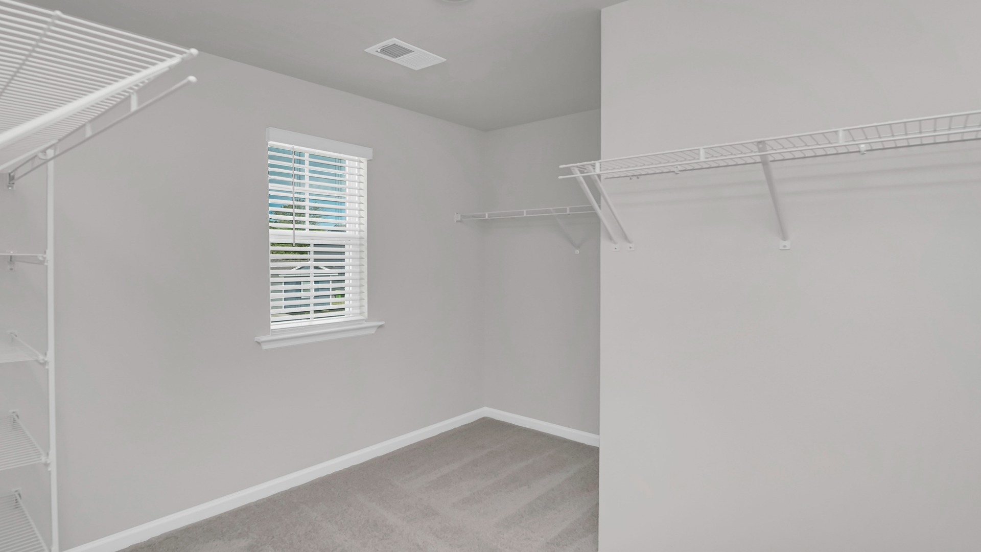 Walk-in primary closet with a window
