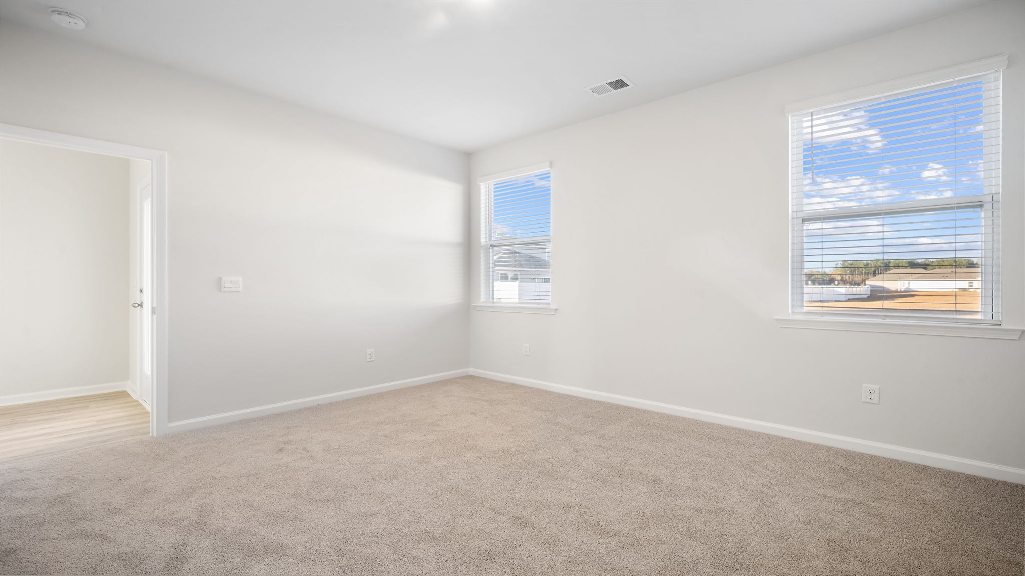 Primary bedroom with several windows and carpet flooring