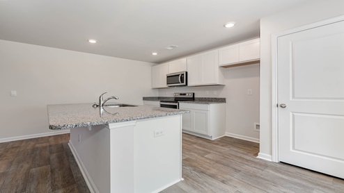 Kerry kitchen with white quartz countertops and white cabinetry.