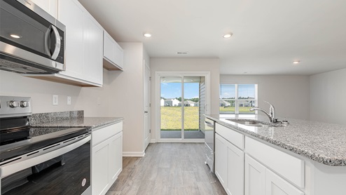 Kerry kitchen with white quartz countertops and white cabinetry.