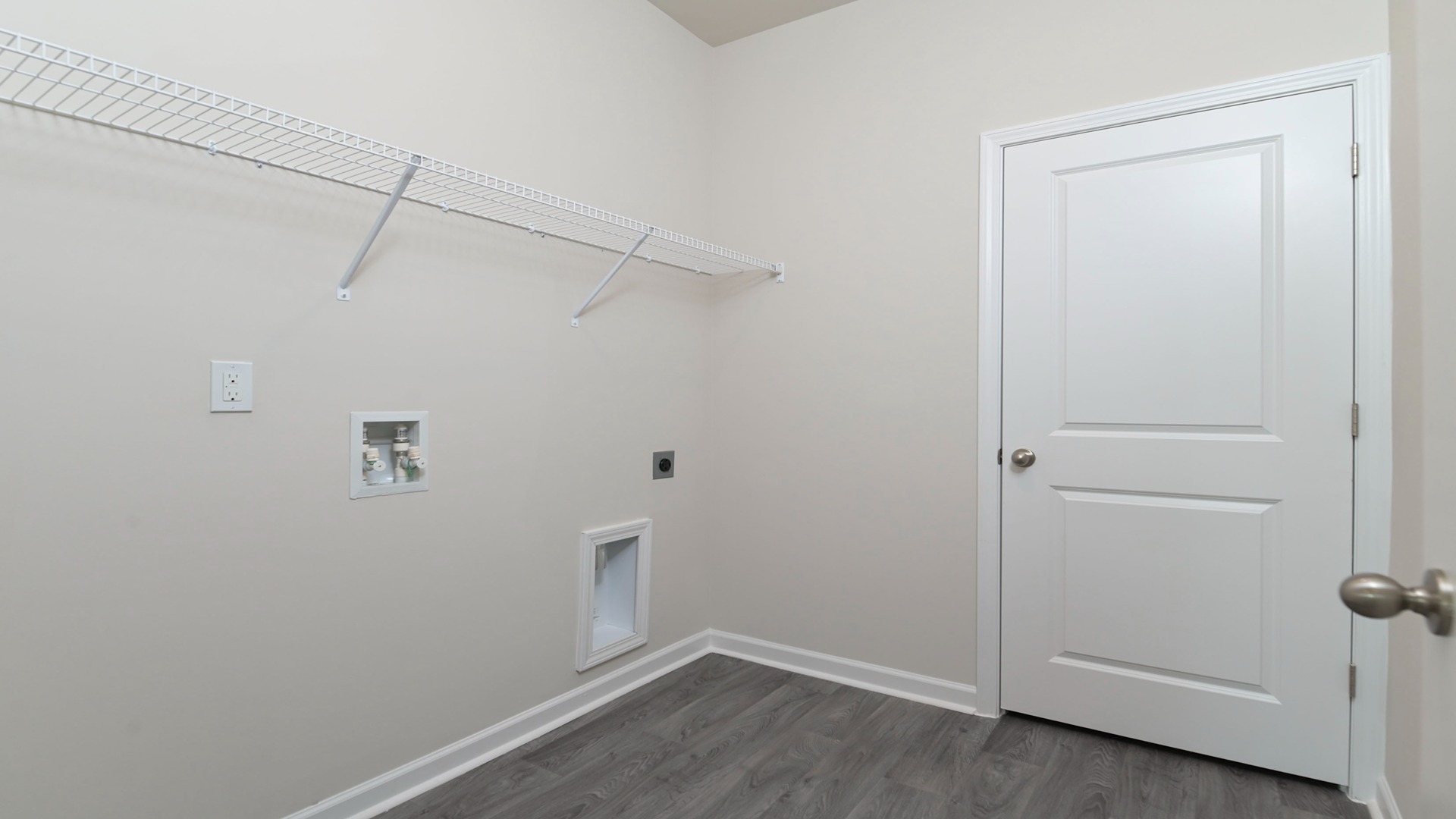 Centrally located laundry room with vinyl flooring and wire shelving above