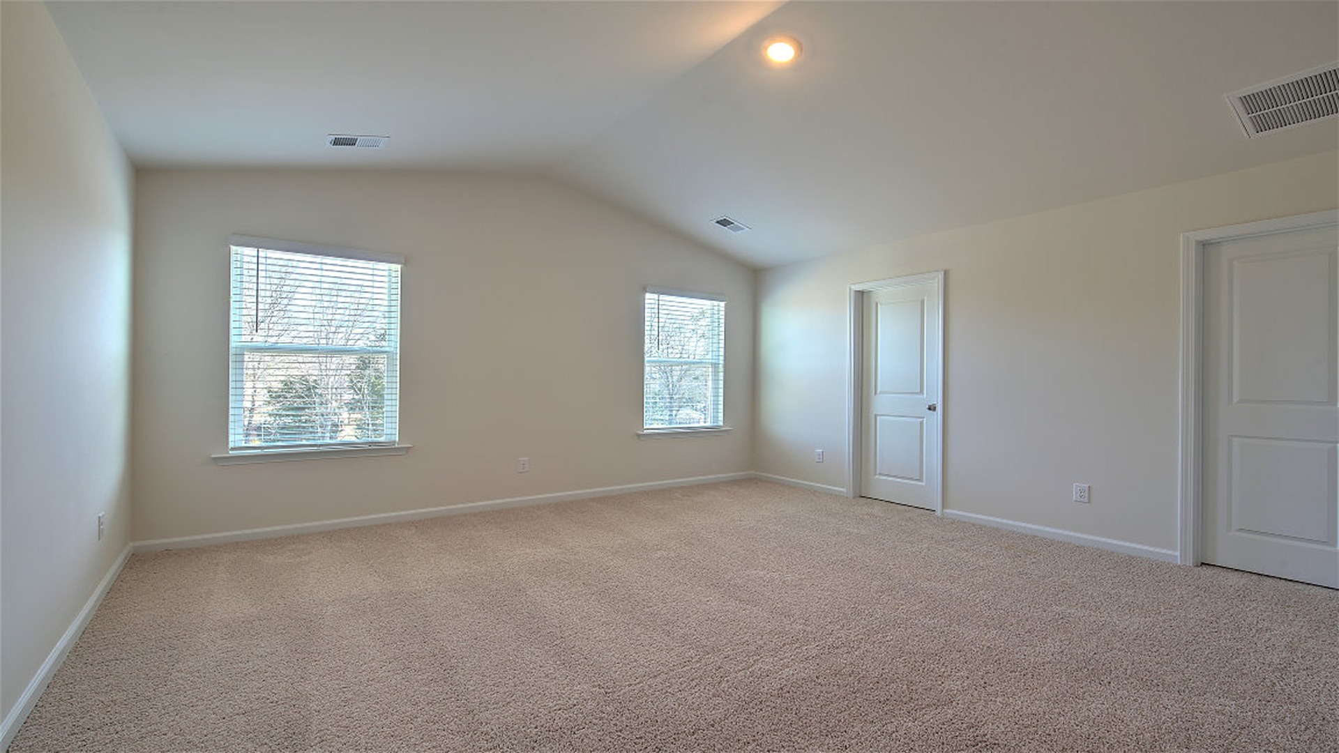 Primary bedroom with vaulted ceilings and several windows