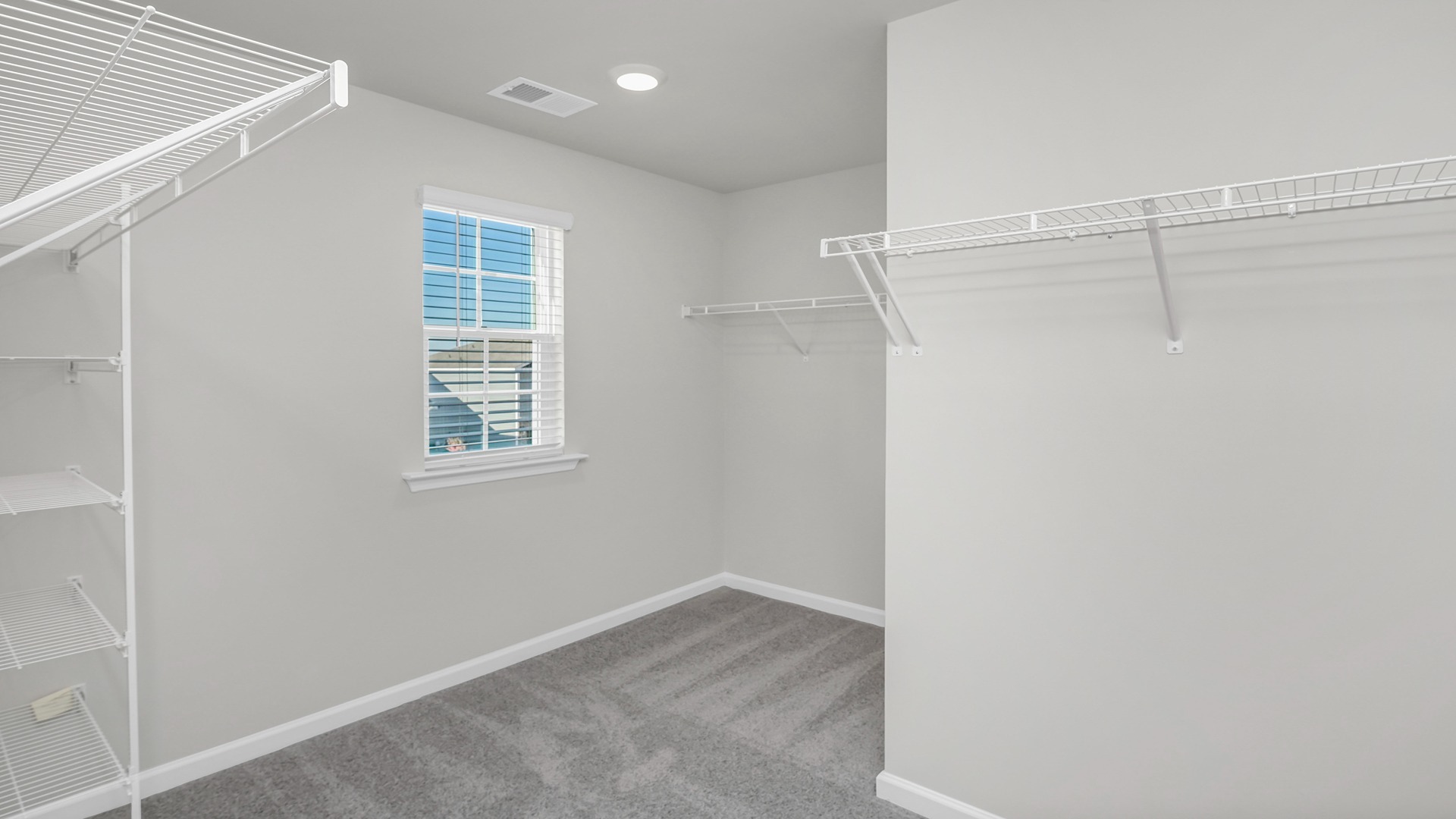 Large walk-in primary closet with a window for light