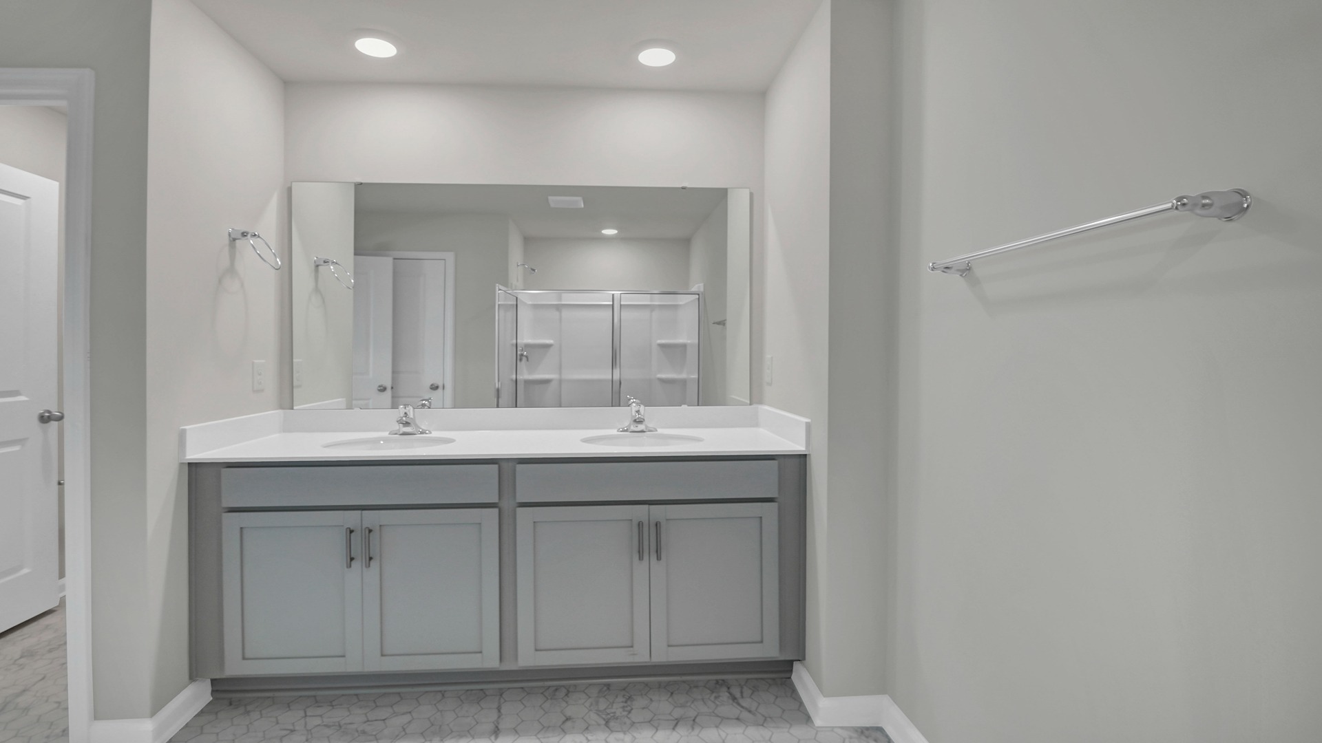 En-suite primary bathroom with double vanity and gray cabinetry