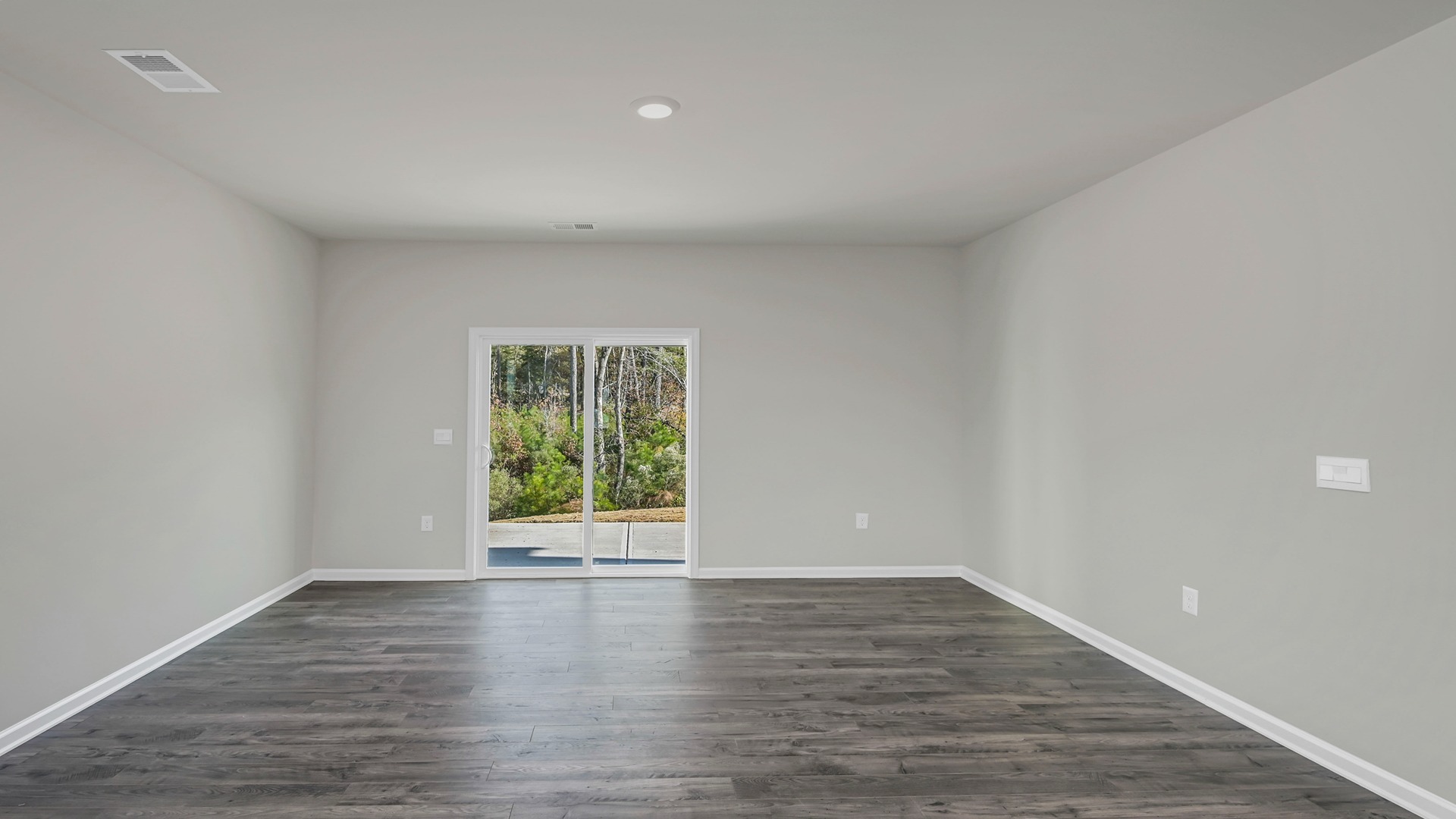 Spacious living area with back sliding doors leading to paved patio