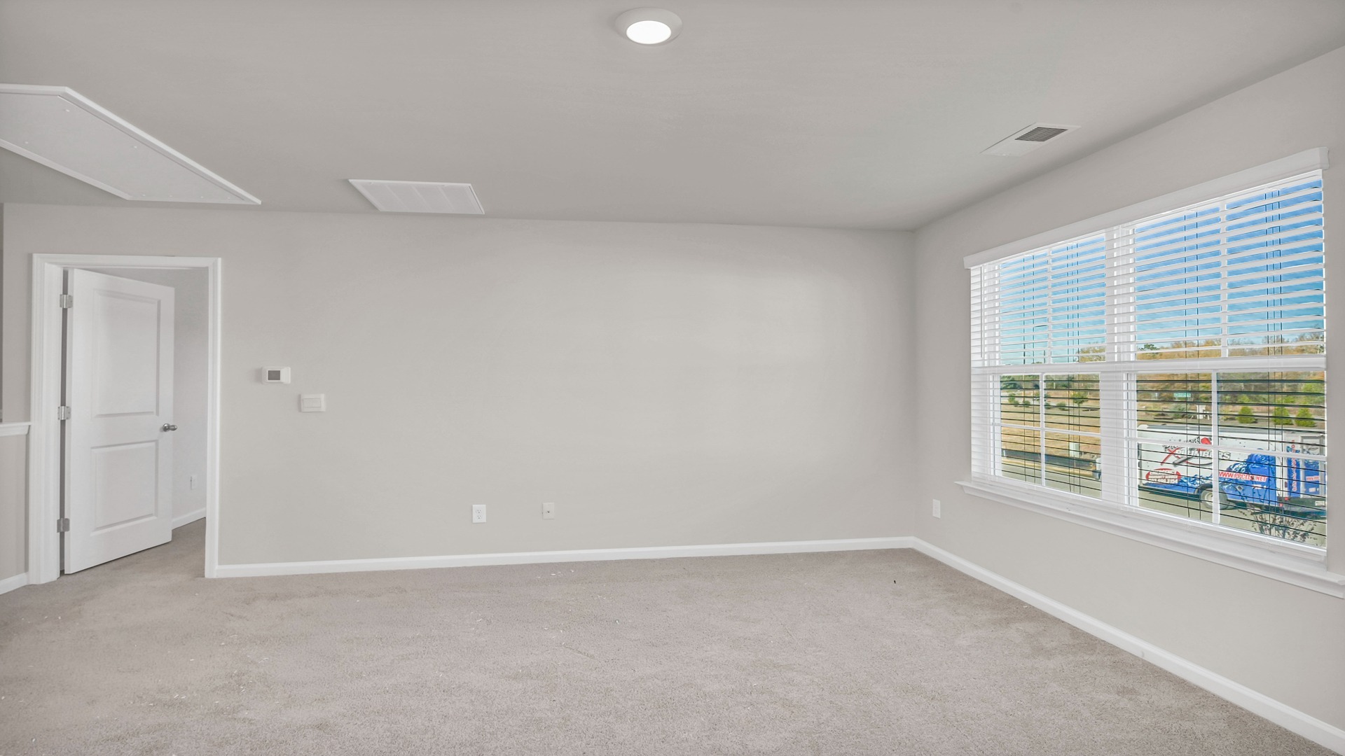 Upstairs living area with large window and carpet flooring