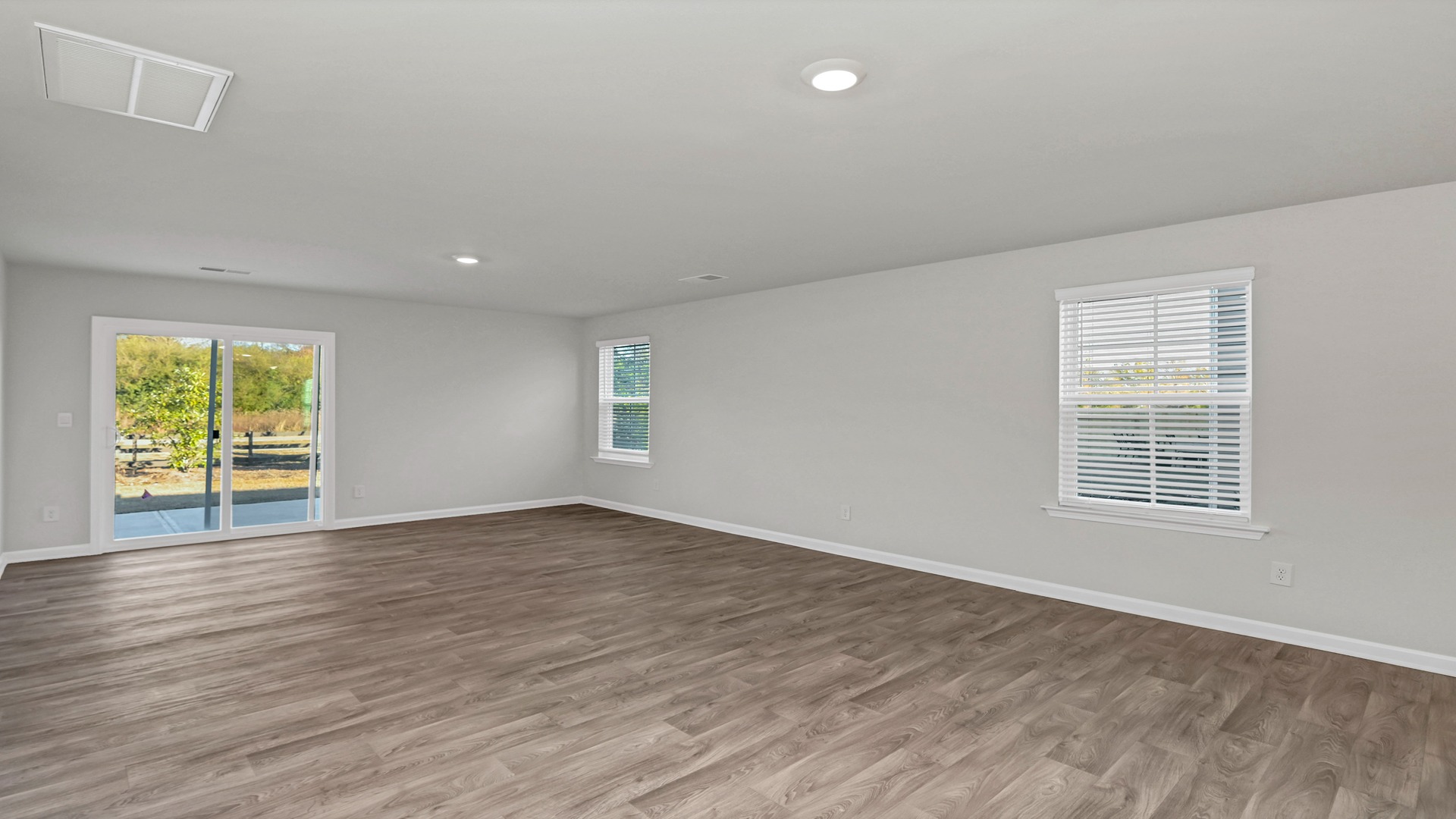 Open concept dining and living areas with matching vinyl floors and natural light