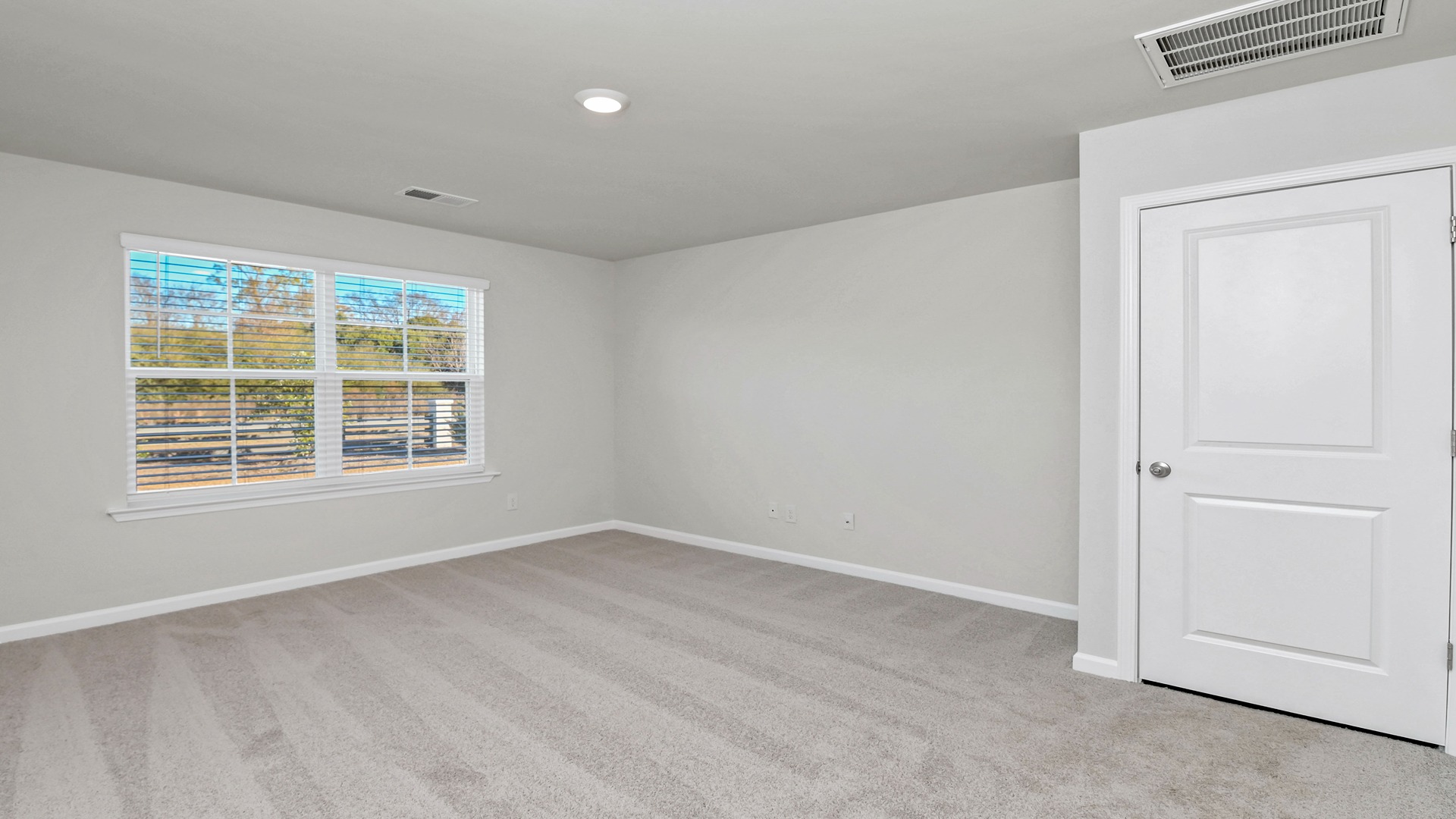 Large window in primary bedroom facing the backyard and carpet floors
