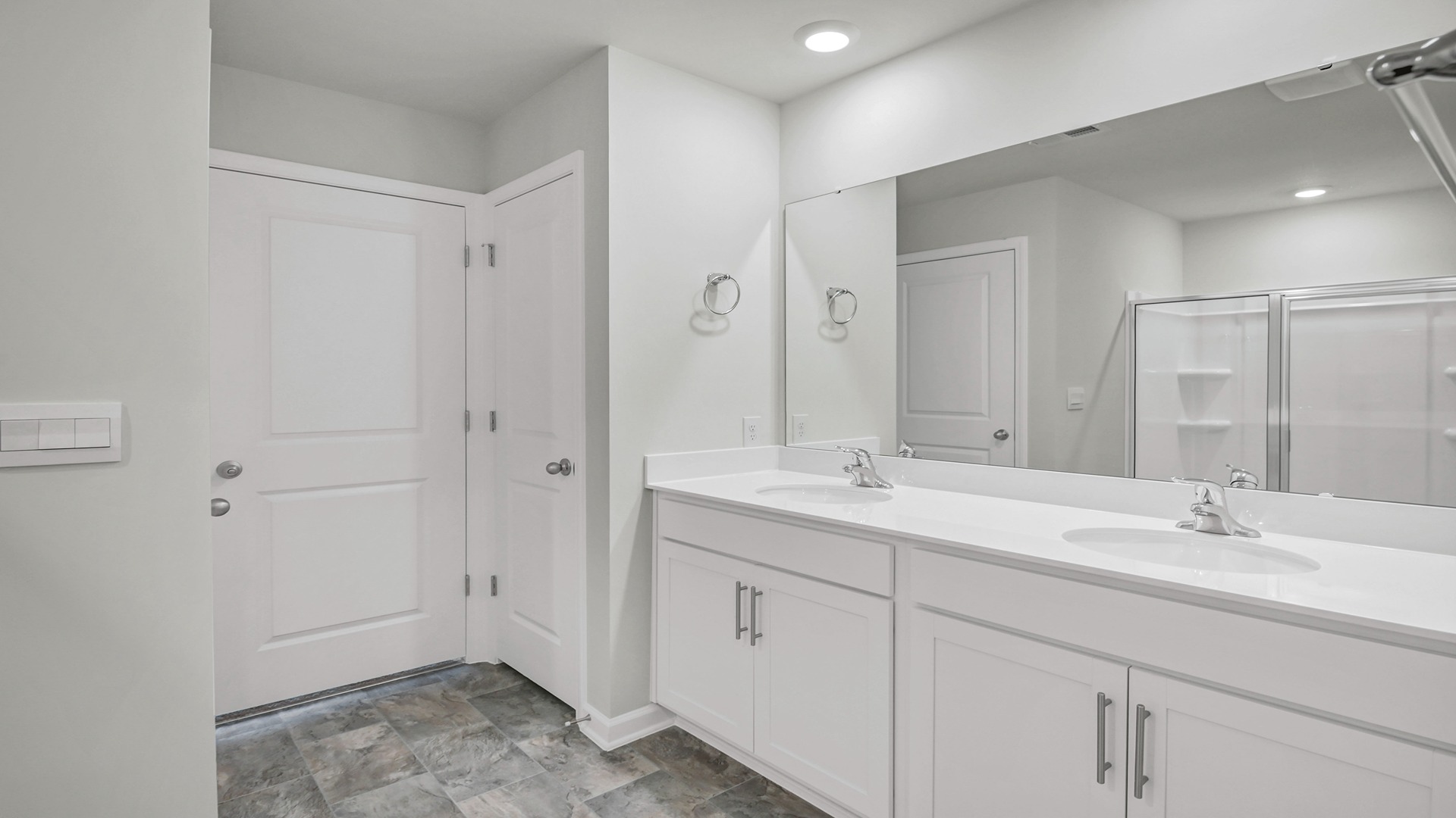 Double vanity, white cabinetry, and standup shower