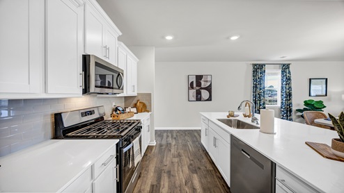 The white quartz countertops and tile backsplash in the kitchen creates a modern, clean look.