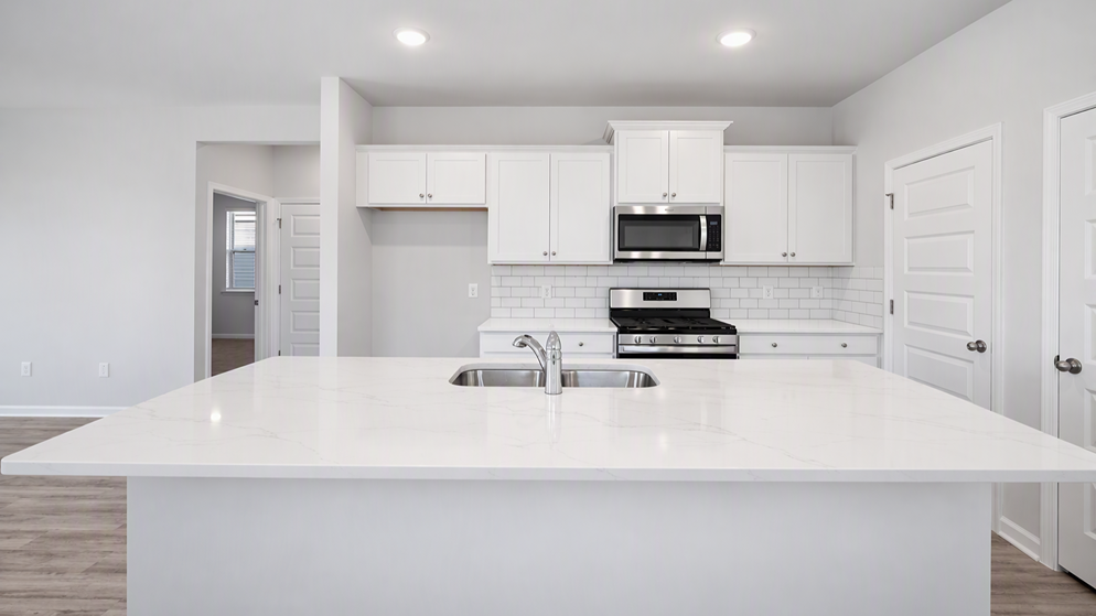 Kitchen in new construction home with white quartz countertops, subway tile backsplash, and white cabinets