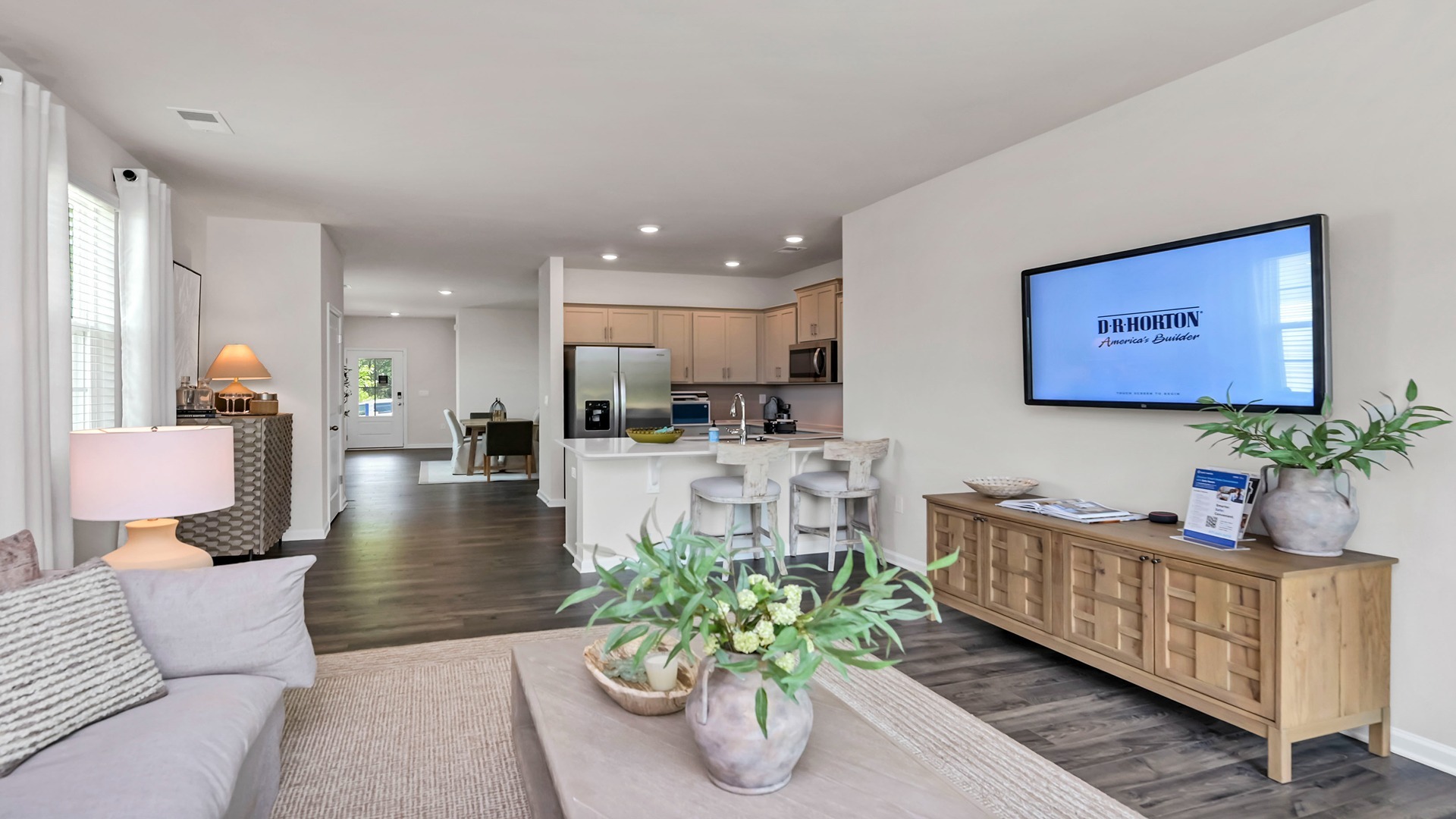 Open concept living and kitchen spaces with matching neutral wall color and RevWood floors