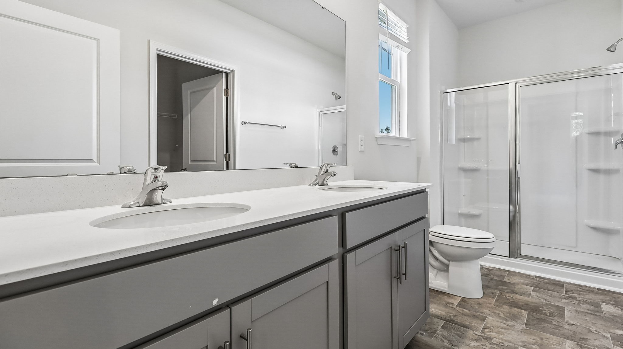 Standup primary shower with glass front in the Kerry primary bathroom and a dual vanity