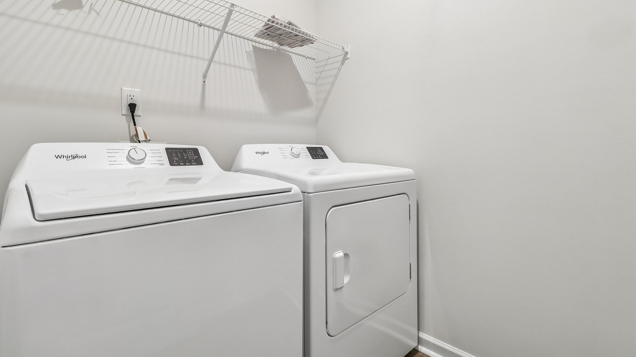 Centrally located laundry room with wire shelving and matching washer and dryer set