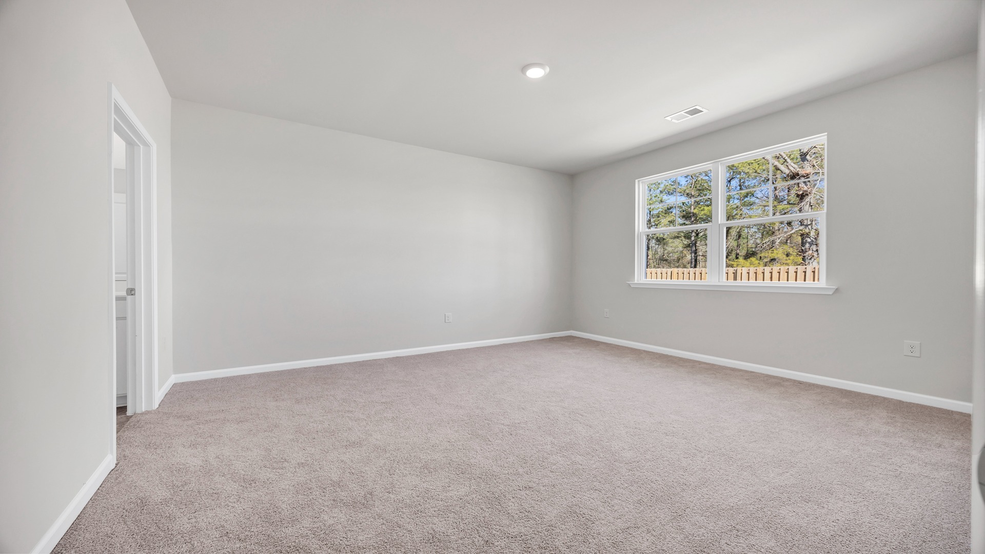 Spacious primary bedroom with a large window facing the backyard