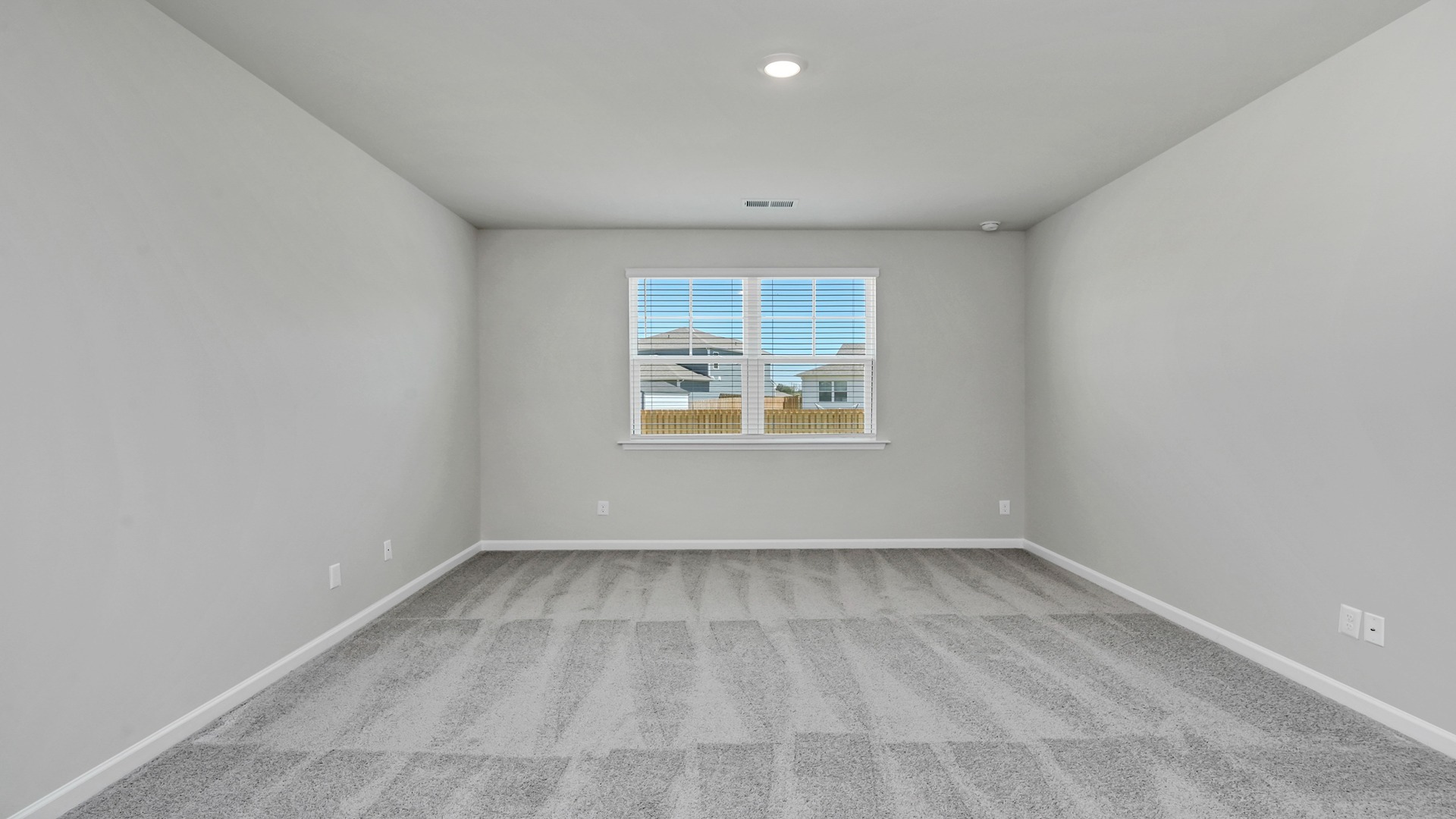Spacious primary bedroom with carpet flooring and a window for natural light