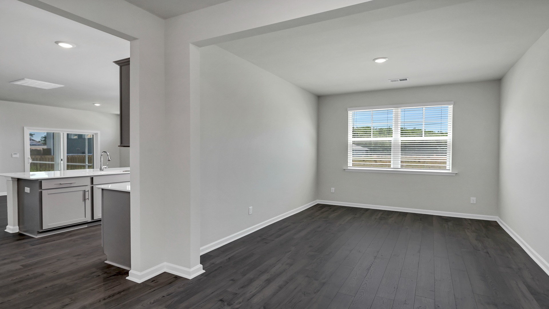 Flex space with a large window leads into the kitchen space