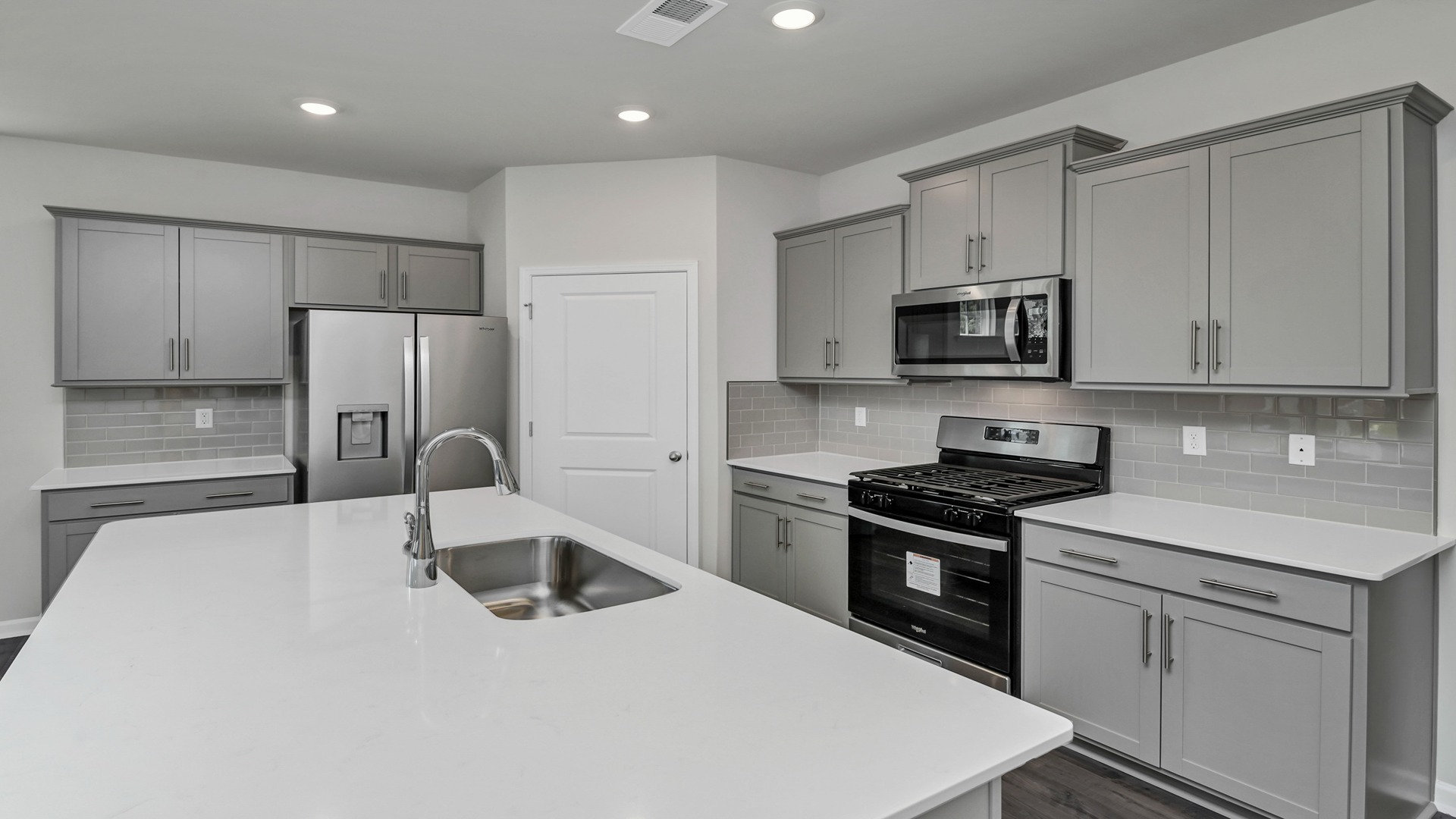 Gray cabinetry and white quartz countertops finish the kitchen in home for sale in Gilbert, SC