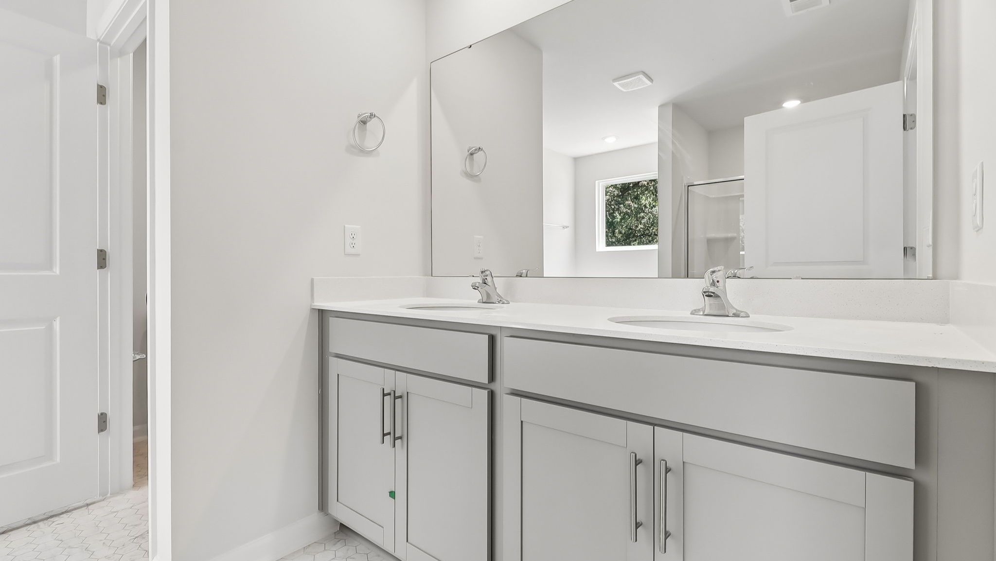 En-suite primary bathroom with double vanity, gray cabinets, and quartz countertops