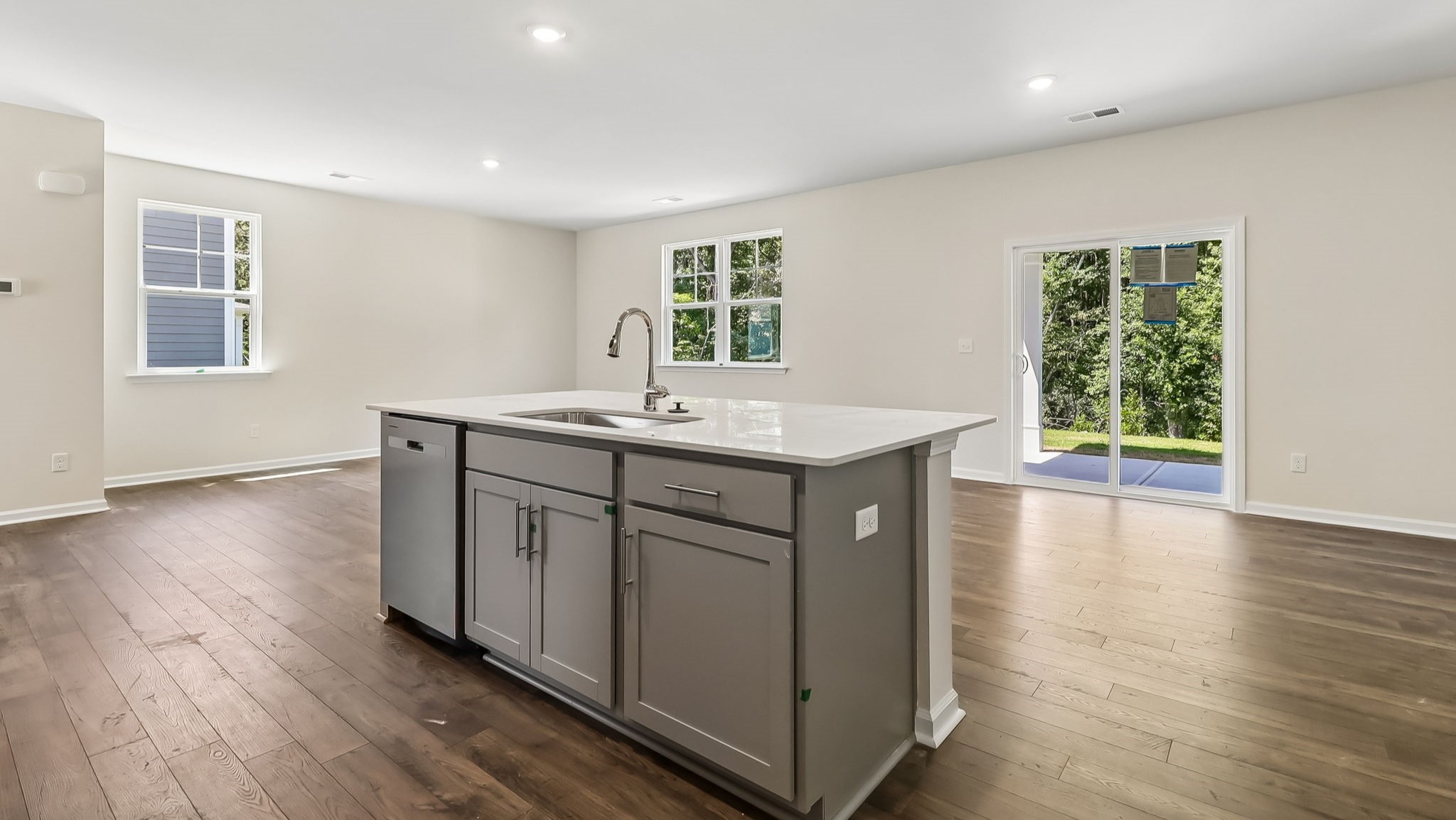 Floating kitchen island overlooking dining and living areas, all with modern vinyl floors