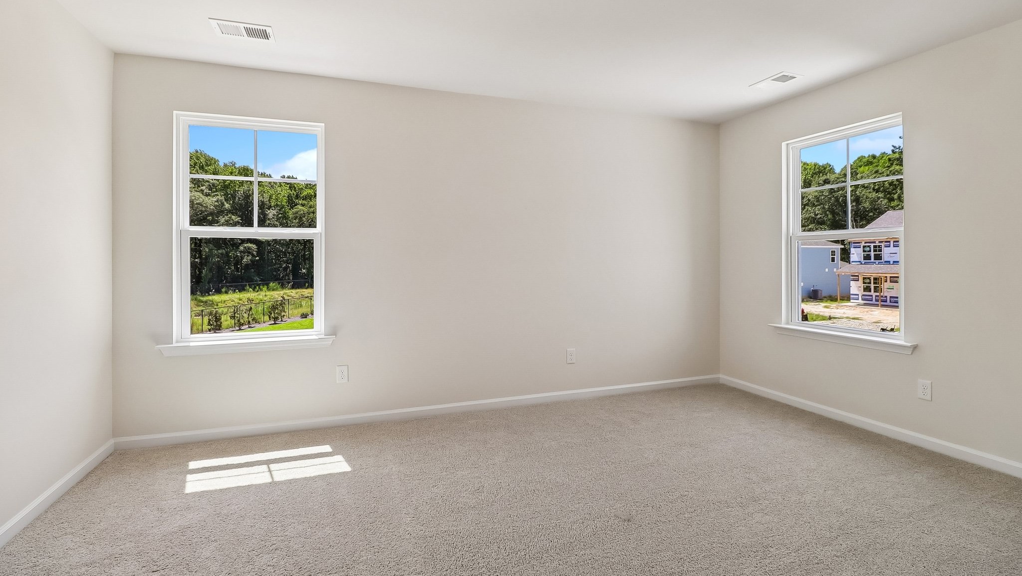 Large primary bedroom upstairs in the Aisle with carpet flooring and two windows for light
