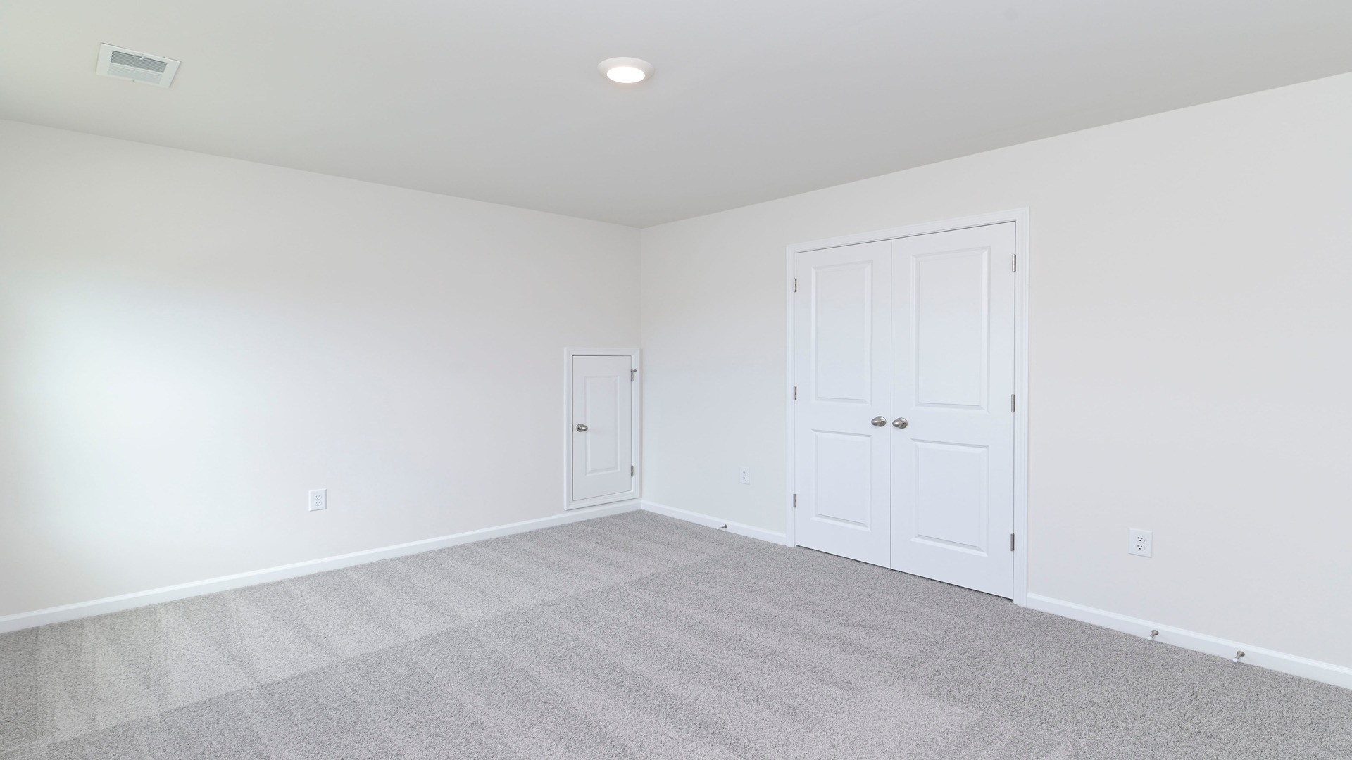 Bedroom in new construction home with French closet doors and plush carpet floors