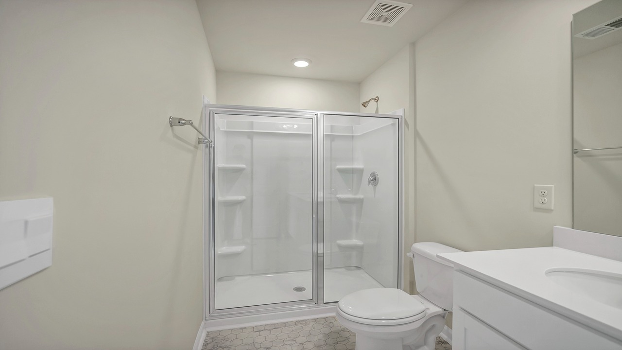 The primary bathroom features a double vanity and a standup shower with glass doors.