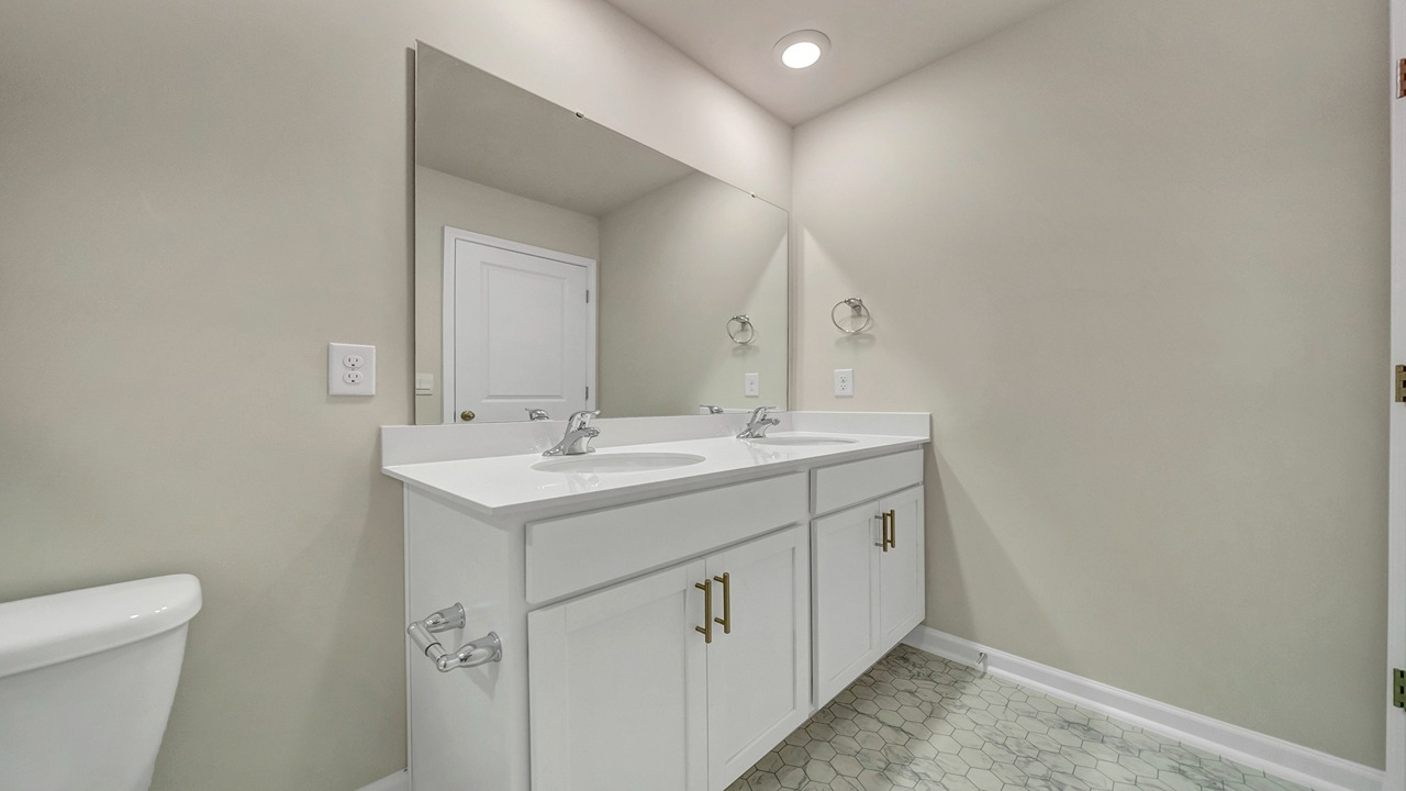 The primary bathroom features a double vanity and a standup shower with glass doors.