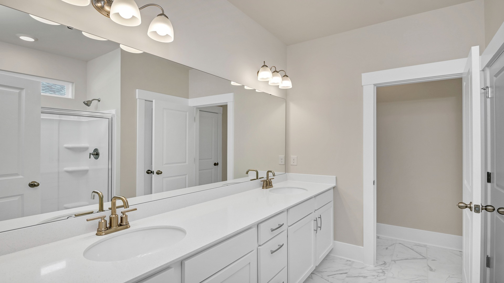 En-suite primary bathroom with double vanity and quartz countertops
