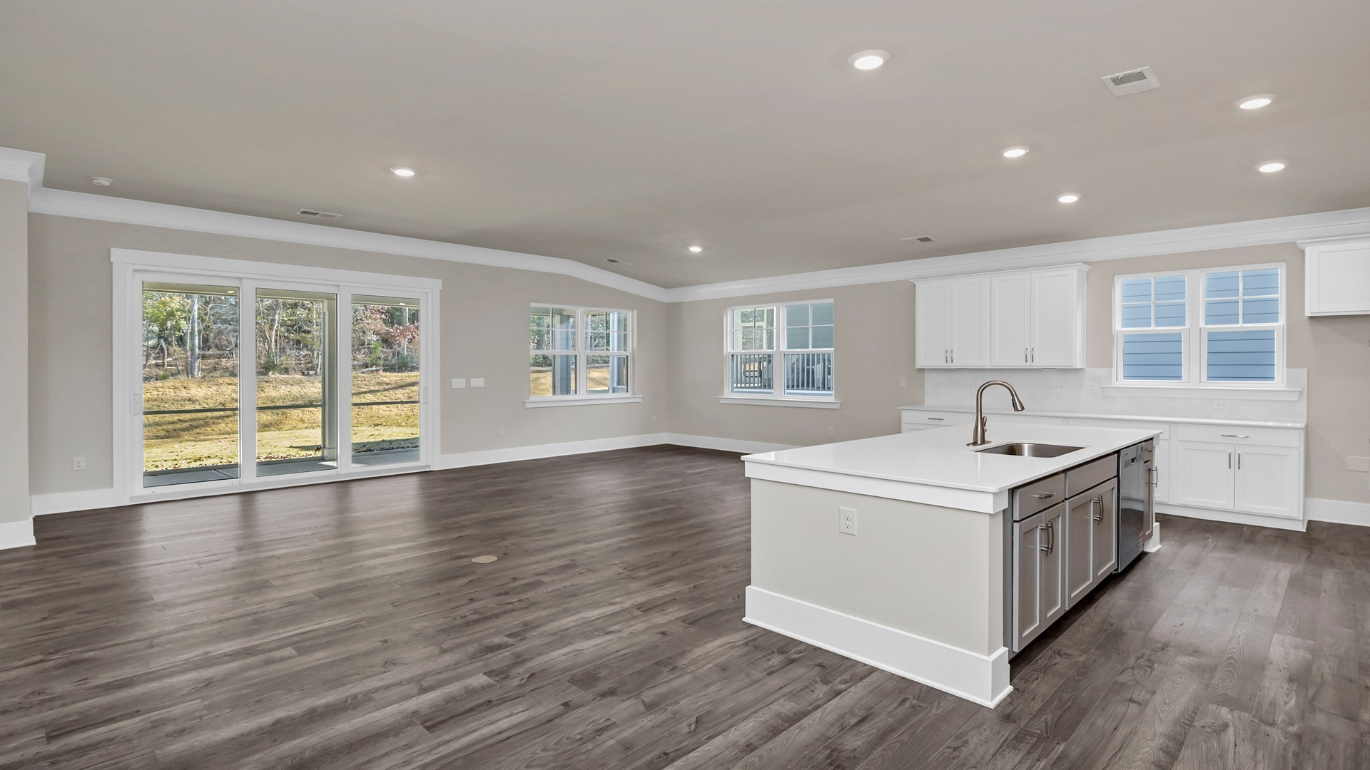 Open concept kitchen, dining, and living areas with natural light and Revwood flooring