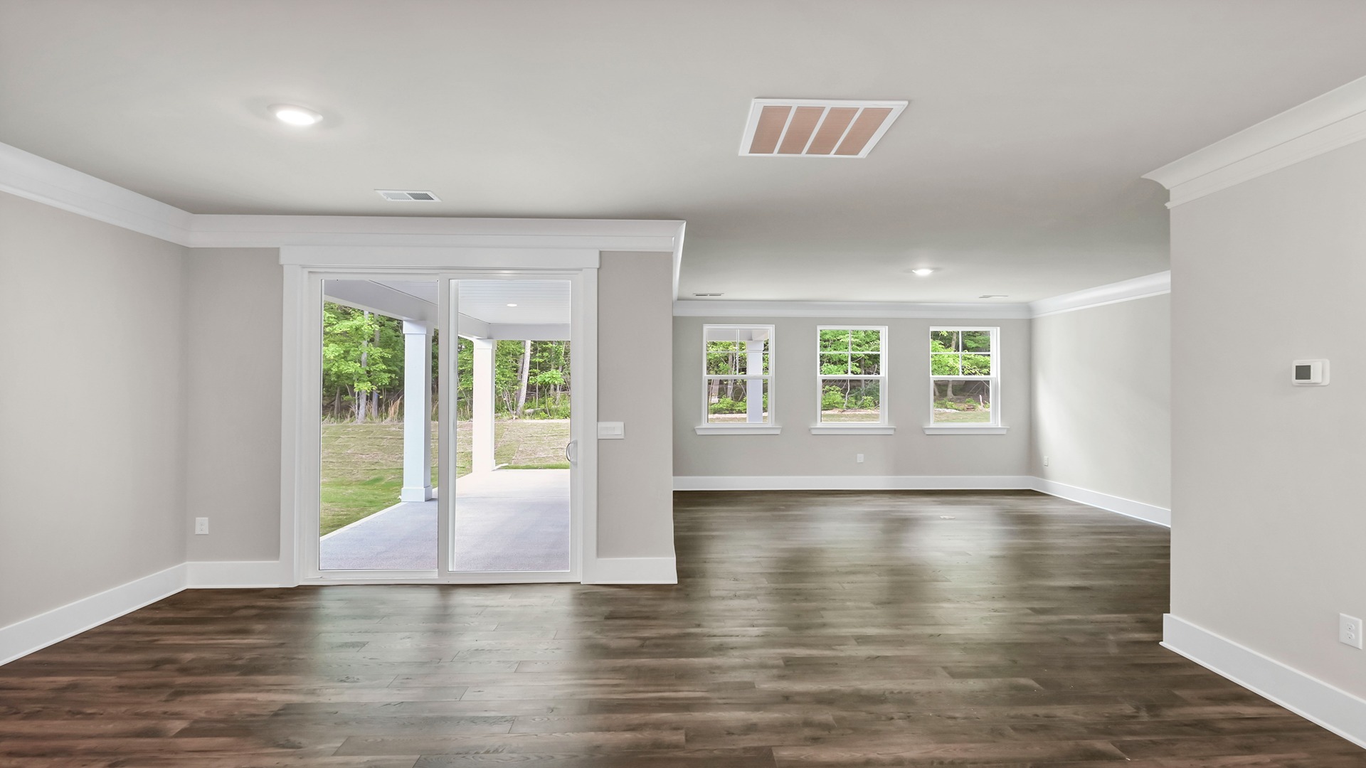 Open concept dining and living areas with RevWood flooring and windows for light