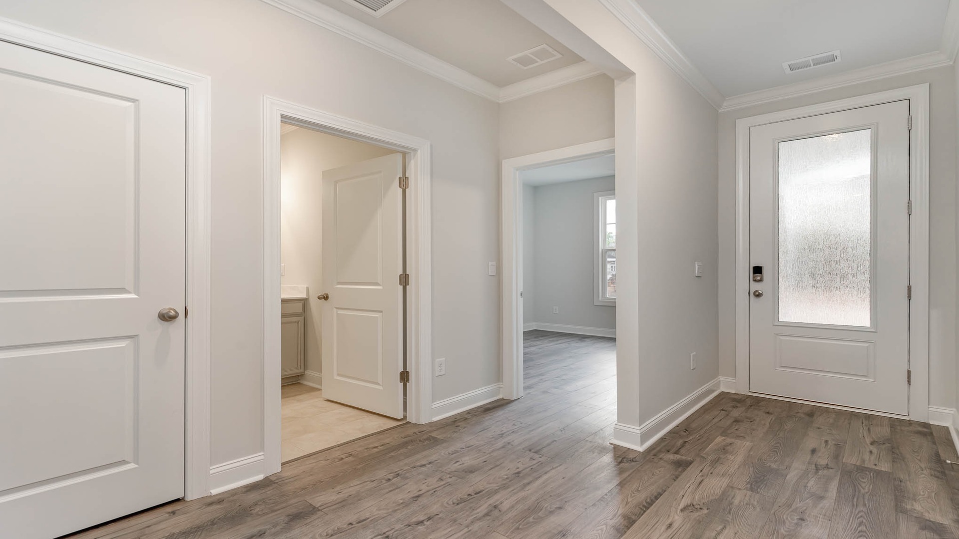 Front foyer of new construction home features natural light and hallways to secondary bedrooms