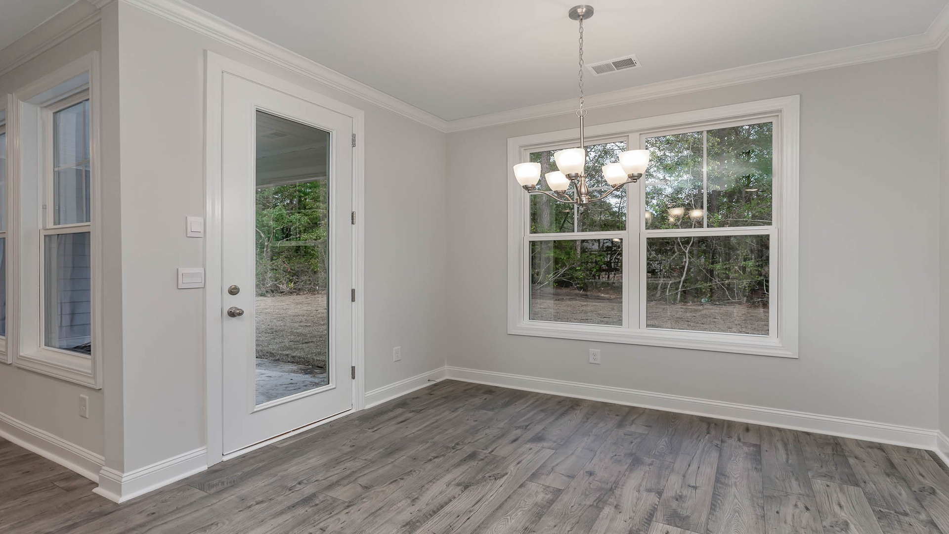 Dining area in the Madison floorplan with a large window facing the backyard and RevWood flooring