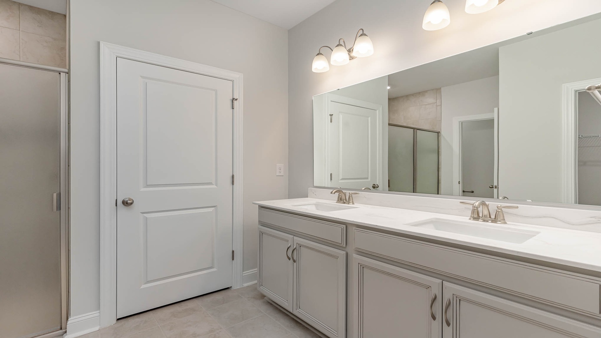 En-suite primary bathroom with a double vanity with quartz countertops and a standup shower