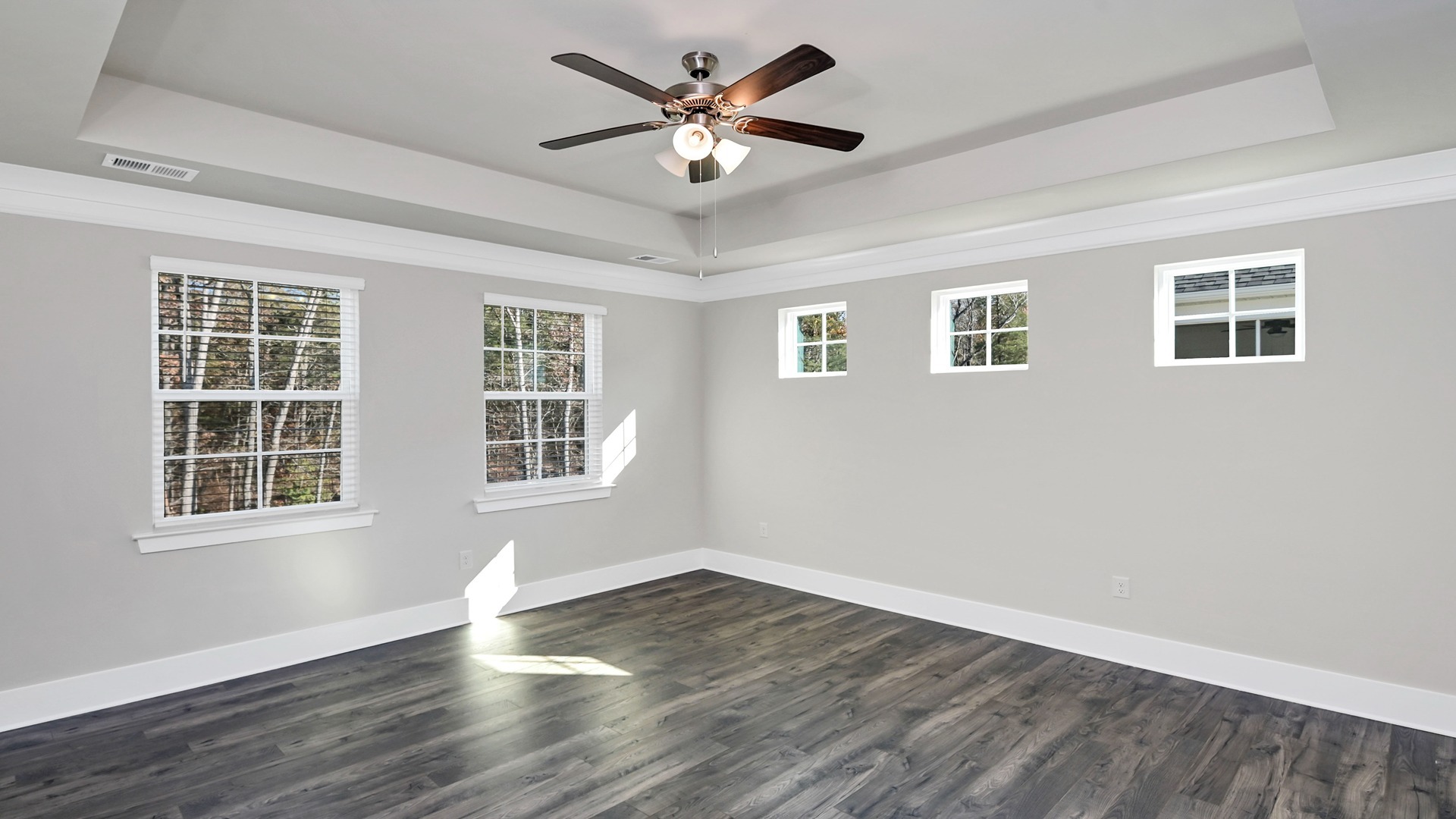 Primary bedroom with RevWood flooring and lots of windows