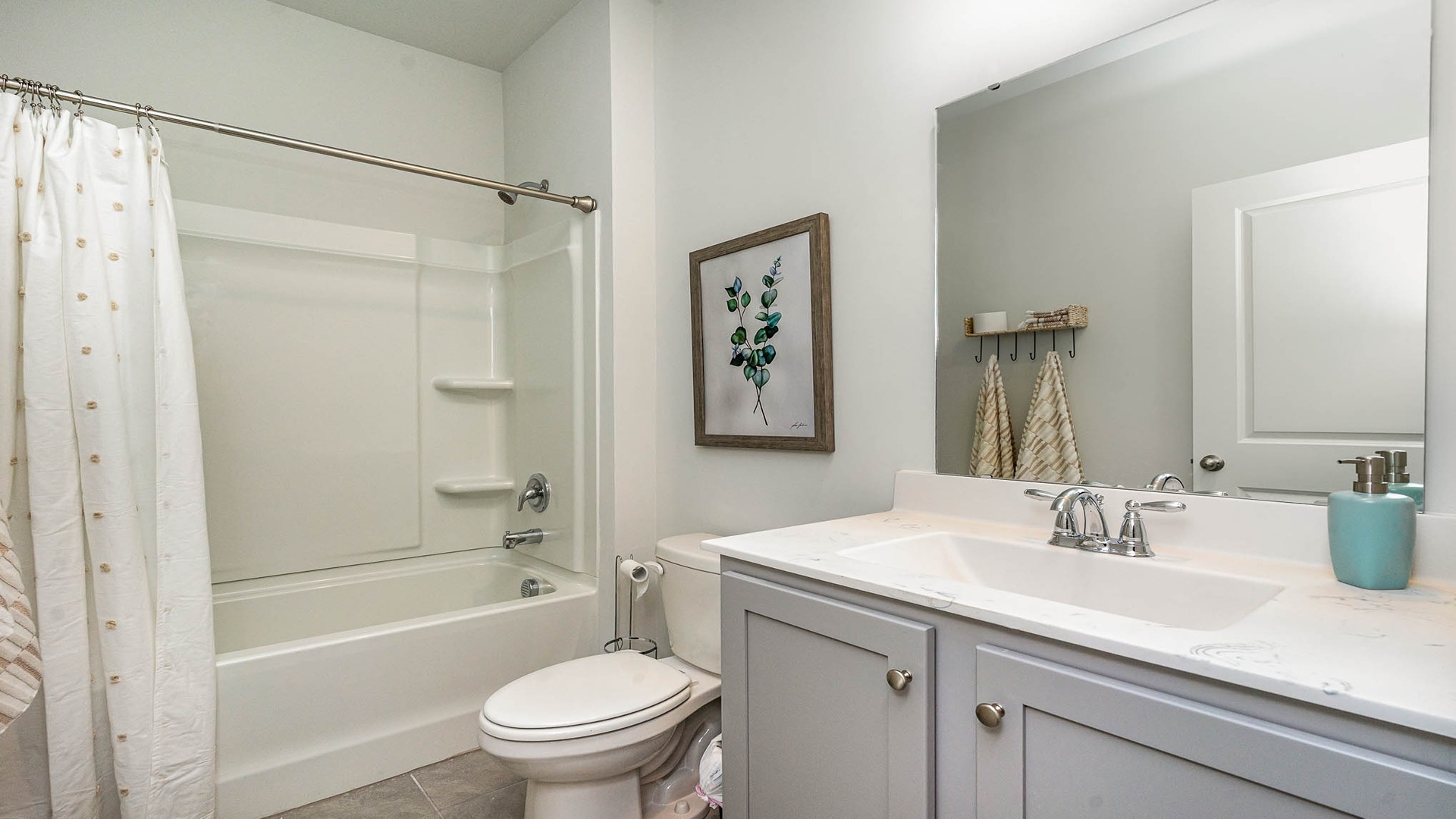 Bathroom 2 with gray cabinets and a shower/tub combo