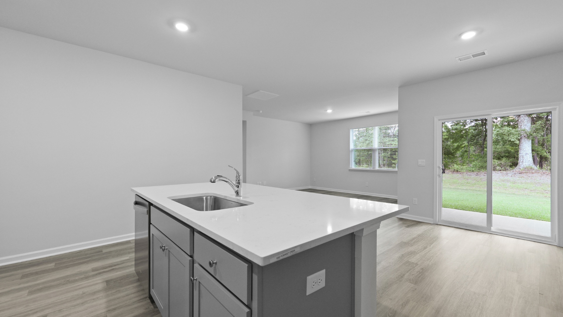 Kitchen sink and dishwasher are on floating kitchen island overlooking dining and living areas