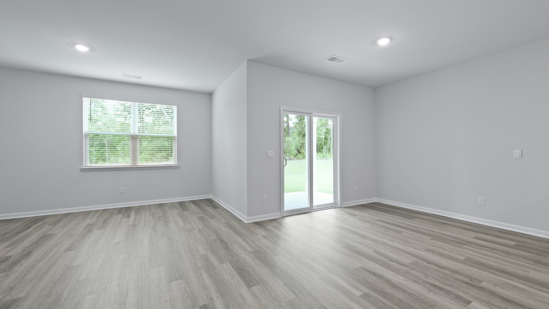 Open concept dining and living areas with vinyl floors and windows for natural light