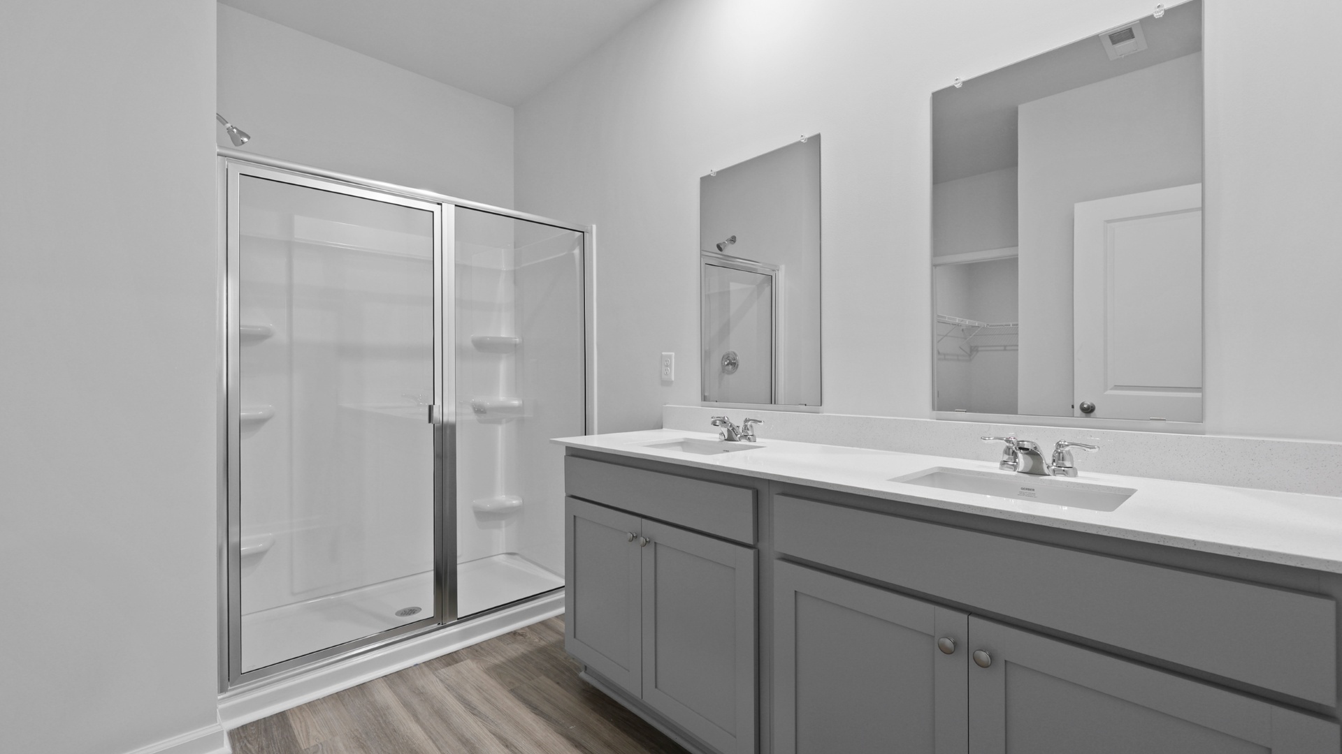 En-suite primary bathroom with a double vanity, standup shower, and gray cabinets
