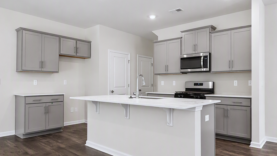 Gray cabinets and white quartz countertops in the kitchen space of new available home