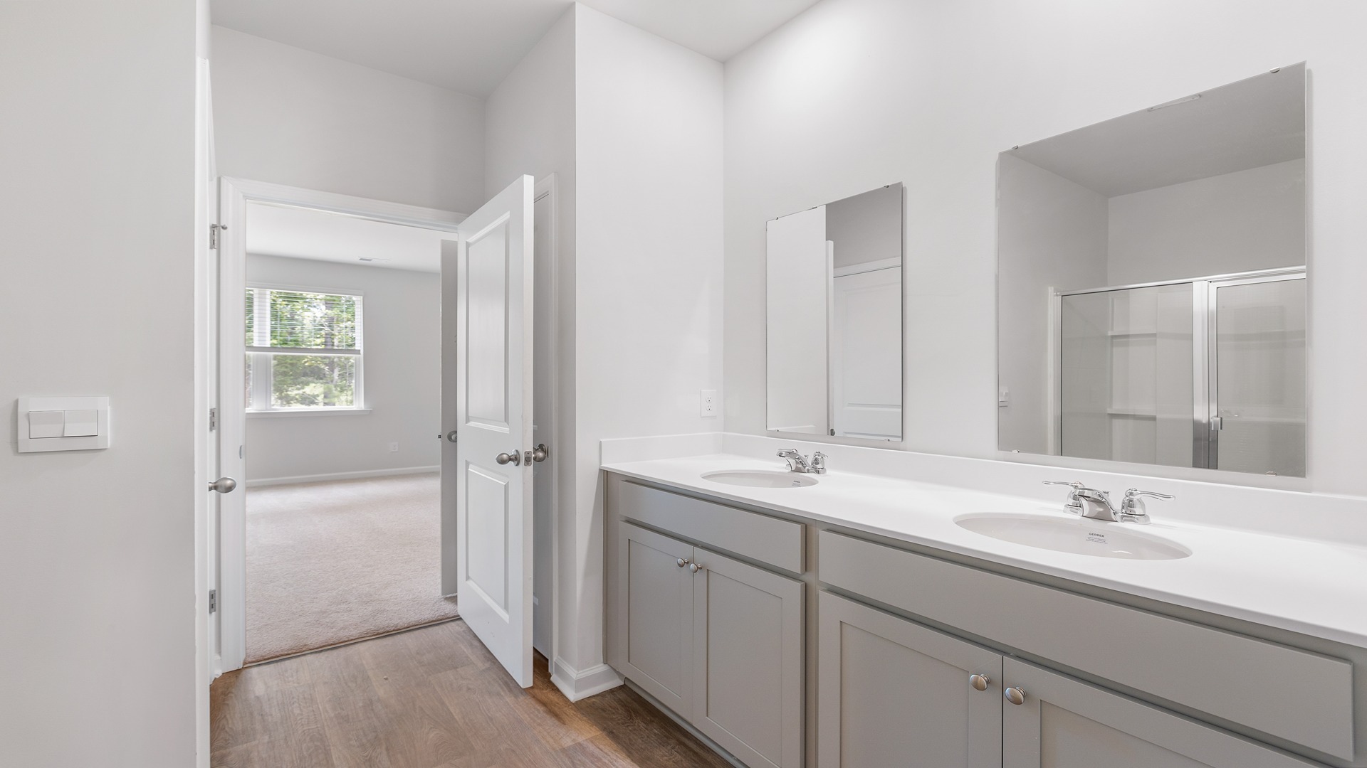 Primary bathroom downstairs with double vanity and gray cabinetry