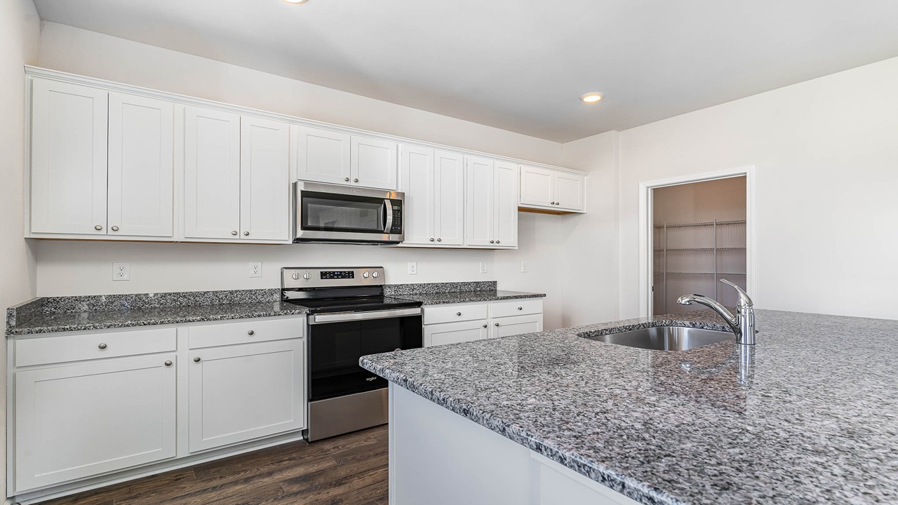 The kitchen space offers shaker-style cabinetry and granite countertops.