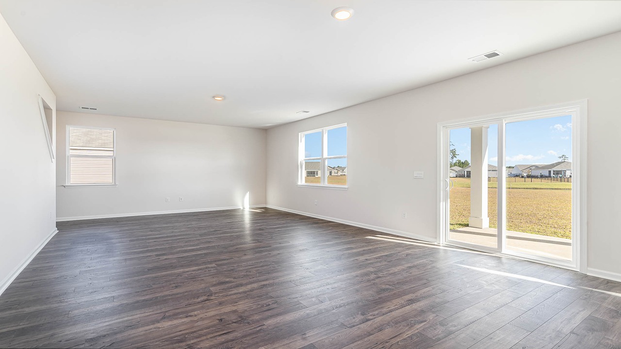 The great room is spacious with several windows and comes finished with wood patterned vinyl flooring.