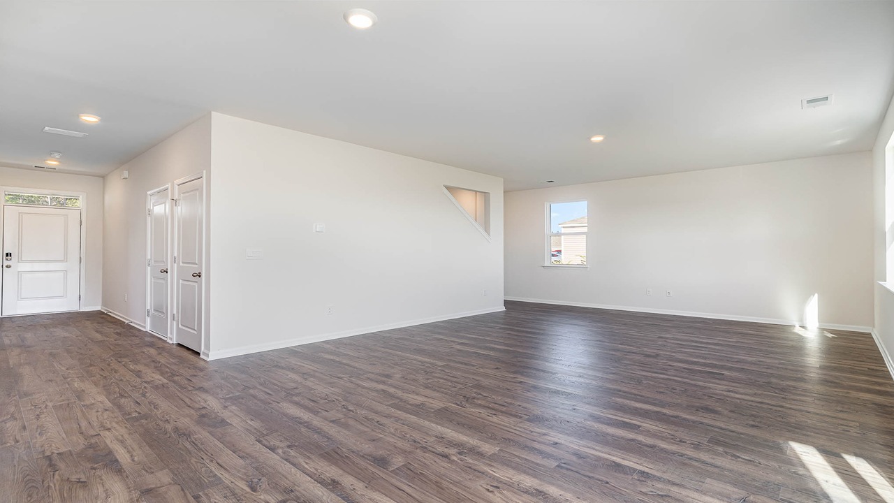 The great room is spacious with several windows and comes finished with wood patterned vinyl flooring.