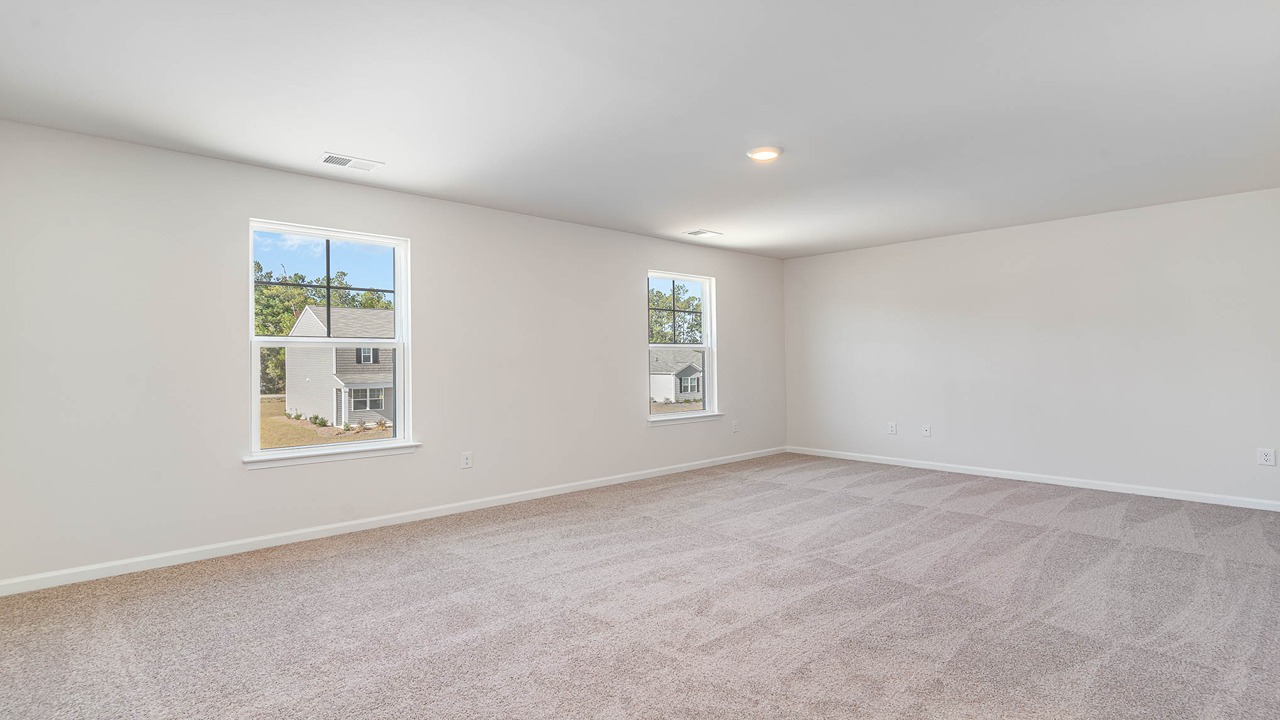 The primary bedroom is spacious upstairs with several windows.